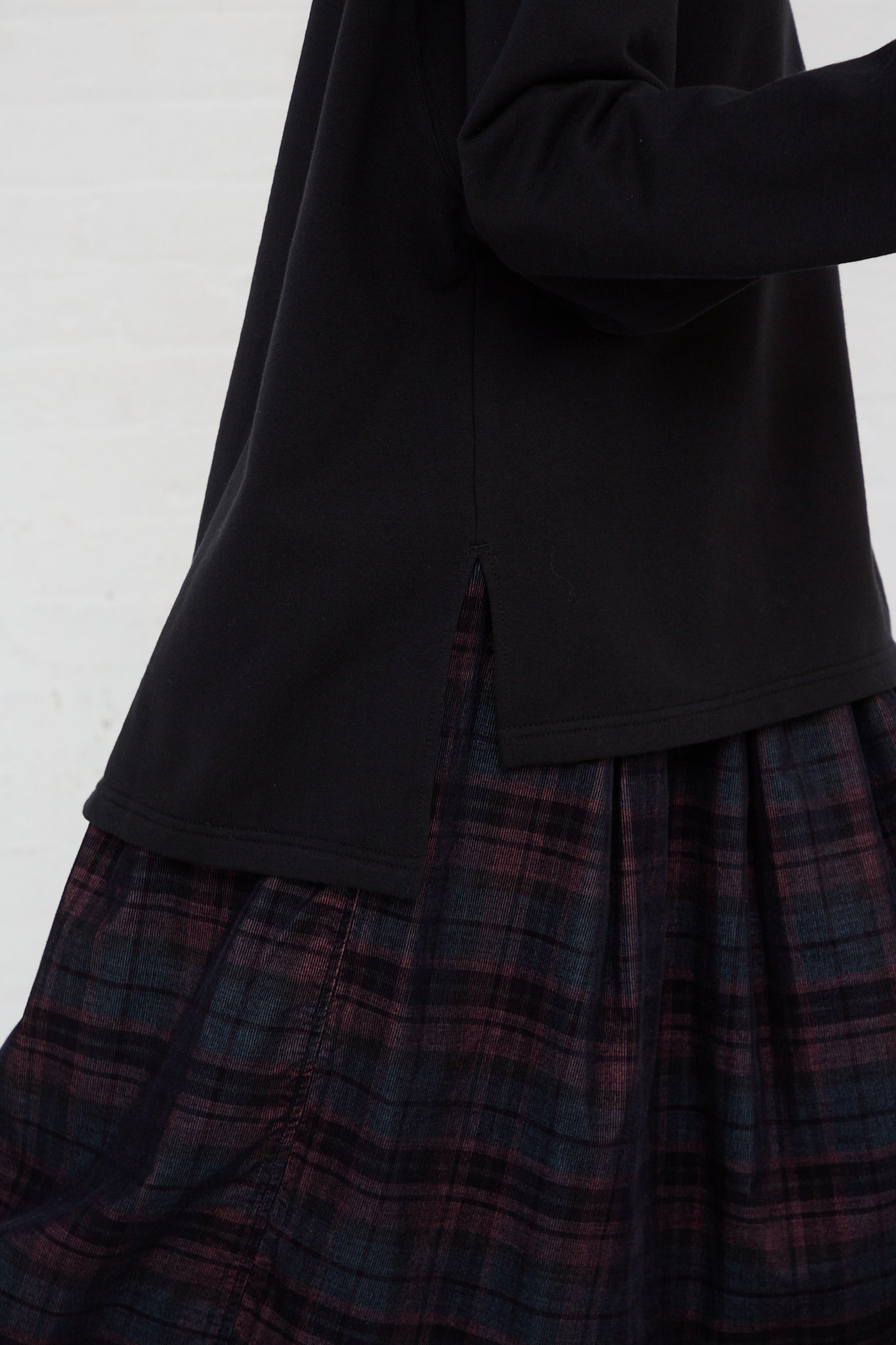The side view of a woman wearing an Ichi Cotton Knit Pullover in Black and plaid skirt.