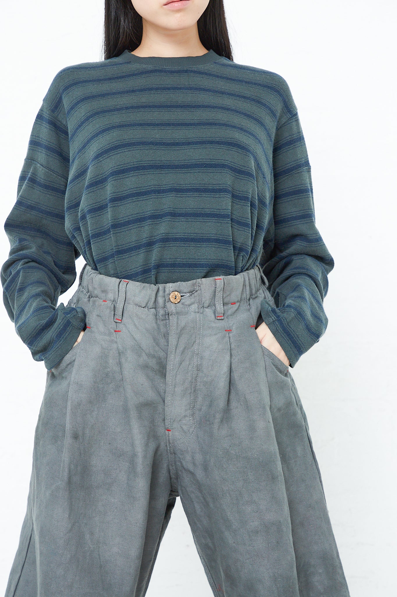 A woman wearing a striped sweater and relaxed fit pants, specifically the 9 oz. Cotton and Hemp P40 Z Boys Military Pant in Swiss Army by Dr. Collectors.