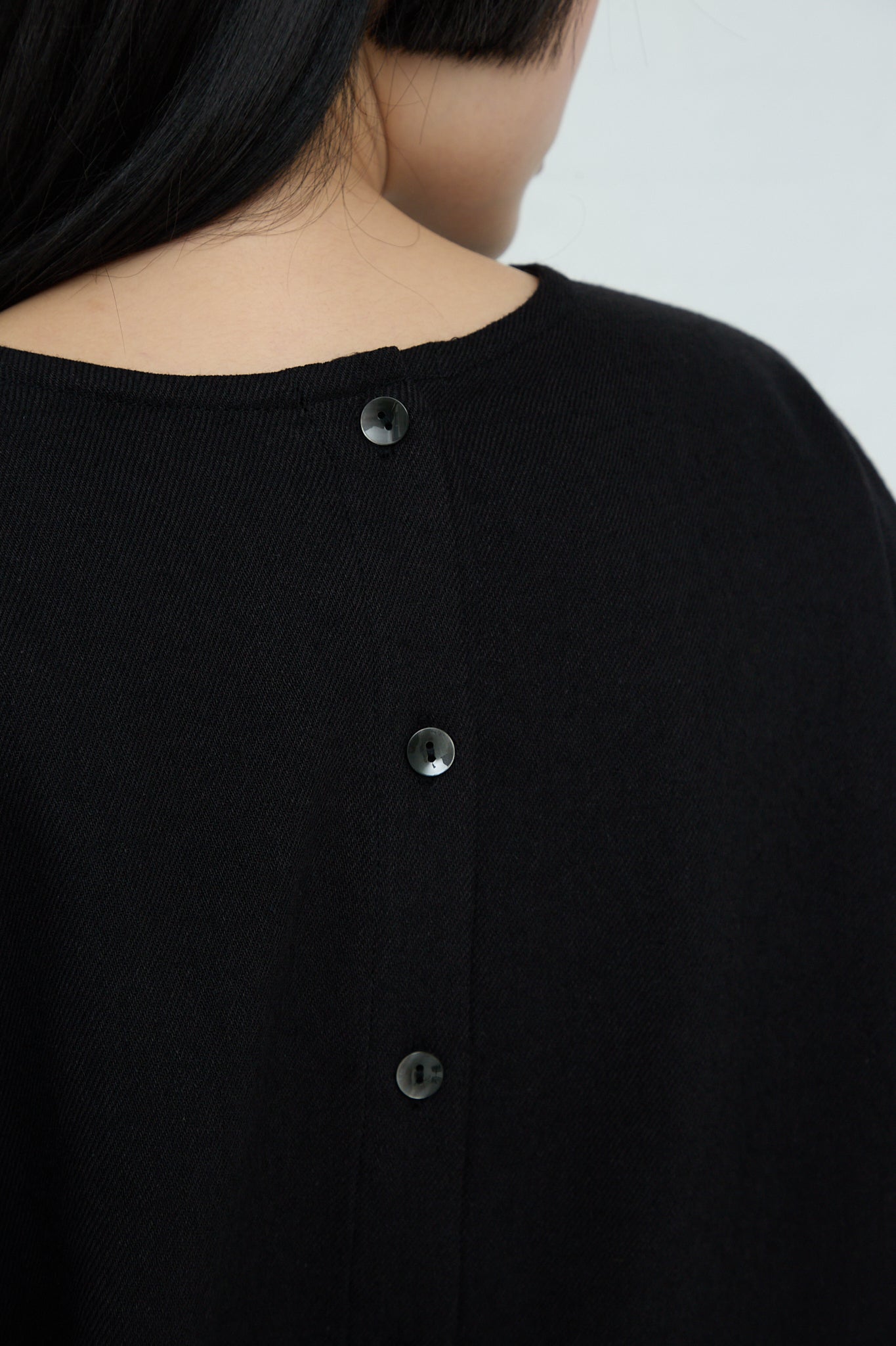 A woman wearing a Ichi Two-Way Blouse in Black, a relaxed fit black sweater in a wool linen blend.