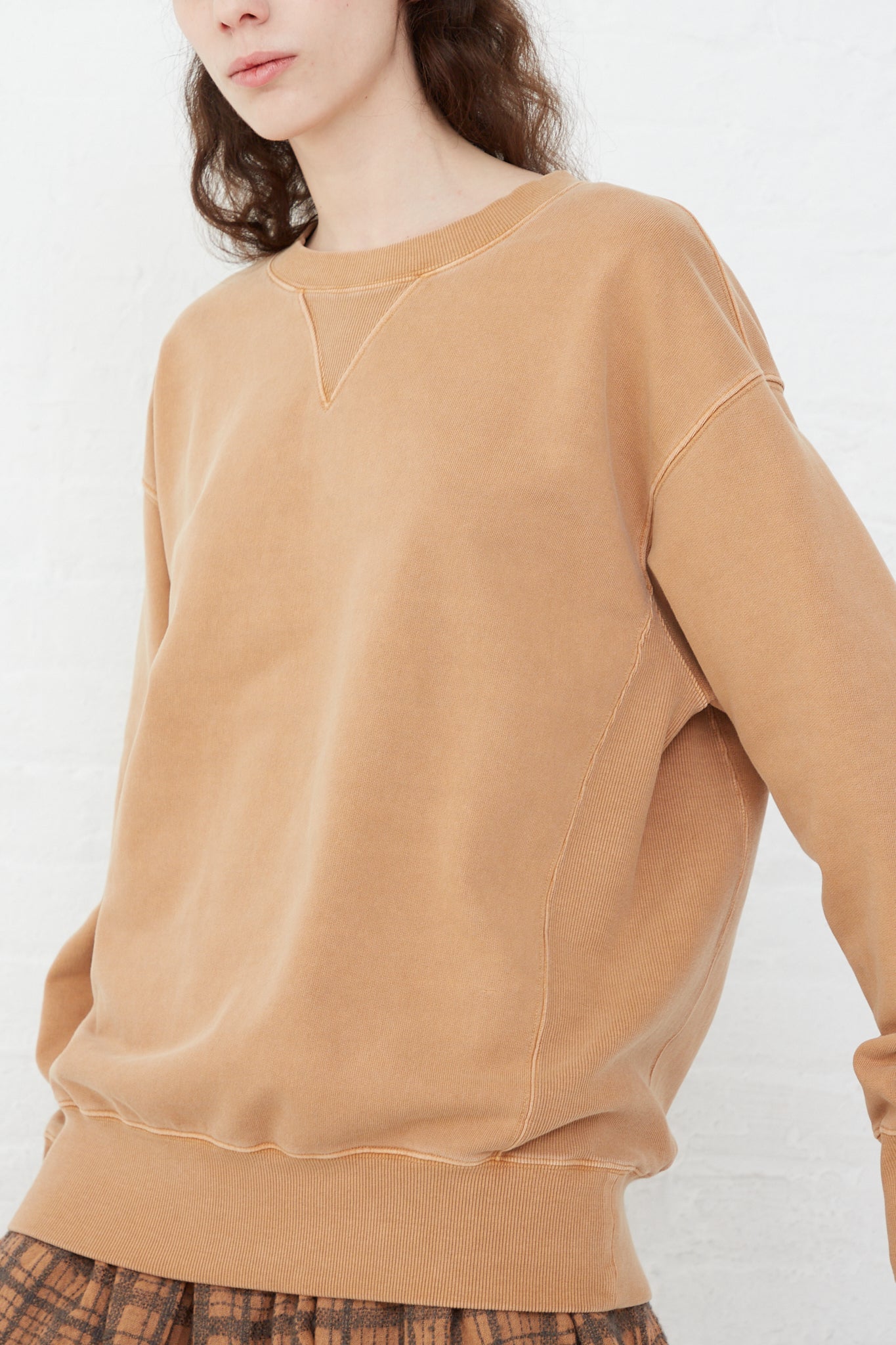 The model is wearing an oversized Ichi Antiquités Pigment French Terry Cotton Pullover in Camel sweatshirt.