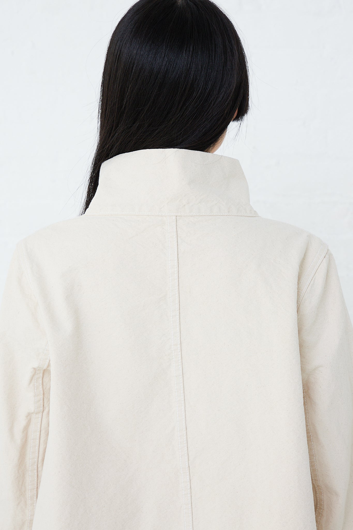 The back view of a woman wearing a Jesse Kamm Organic Canvas Deck Jacket in Natural.