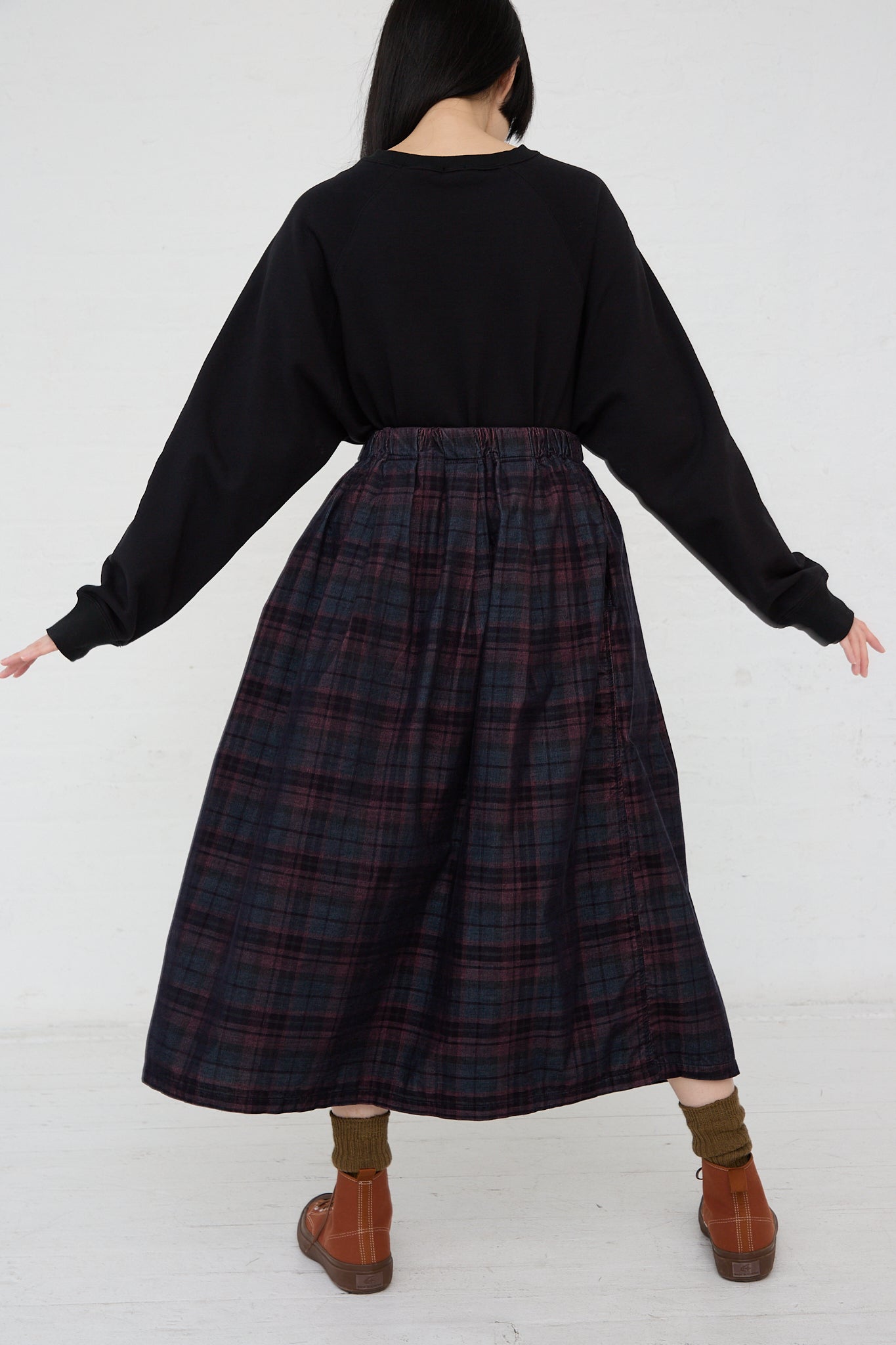A woman wearing a black sweater and Ichi's plaid Woven Cotton Skirt in Navy with an elasticated waist. Back view.