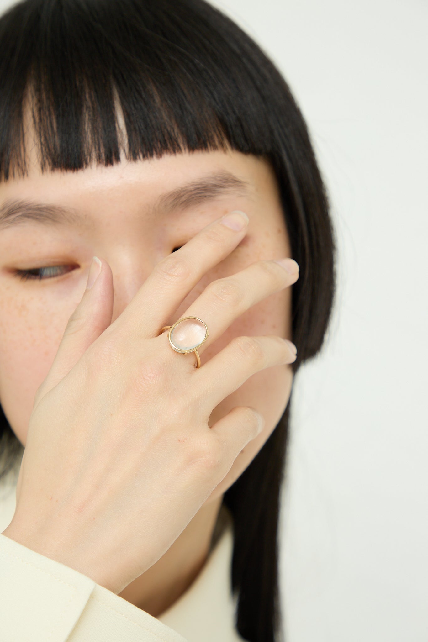 A Mary MacGill woman with black hair covering her face with a 14K Floating Ring in Crystal Quartz.