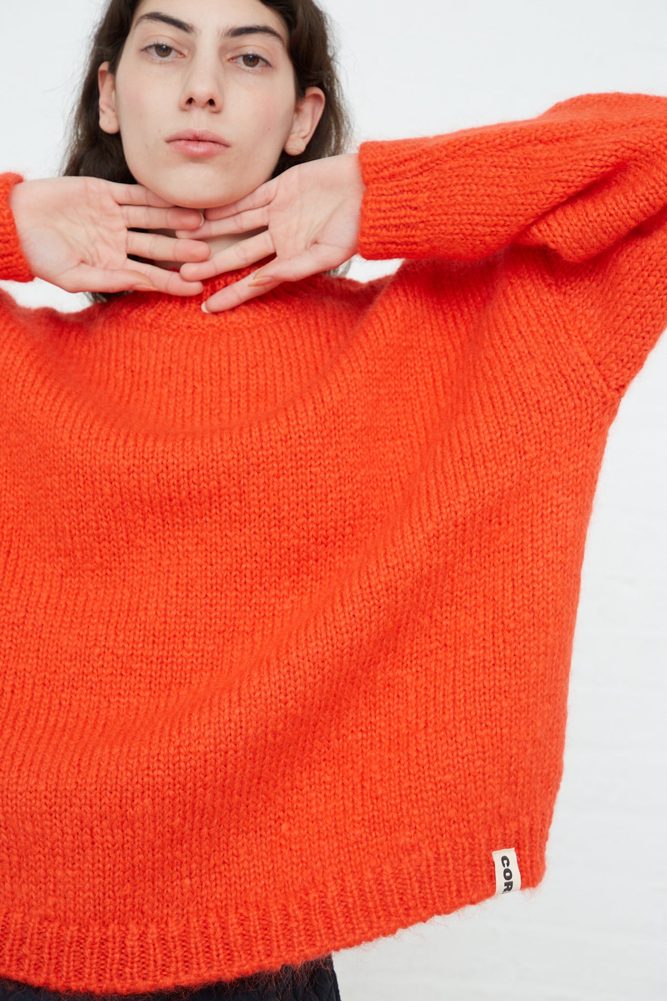A woman wearing a Cordera oversized crew neck sweater in a Tangerine Mohair blend.