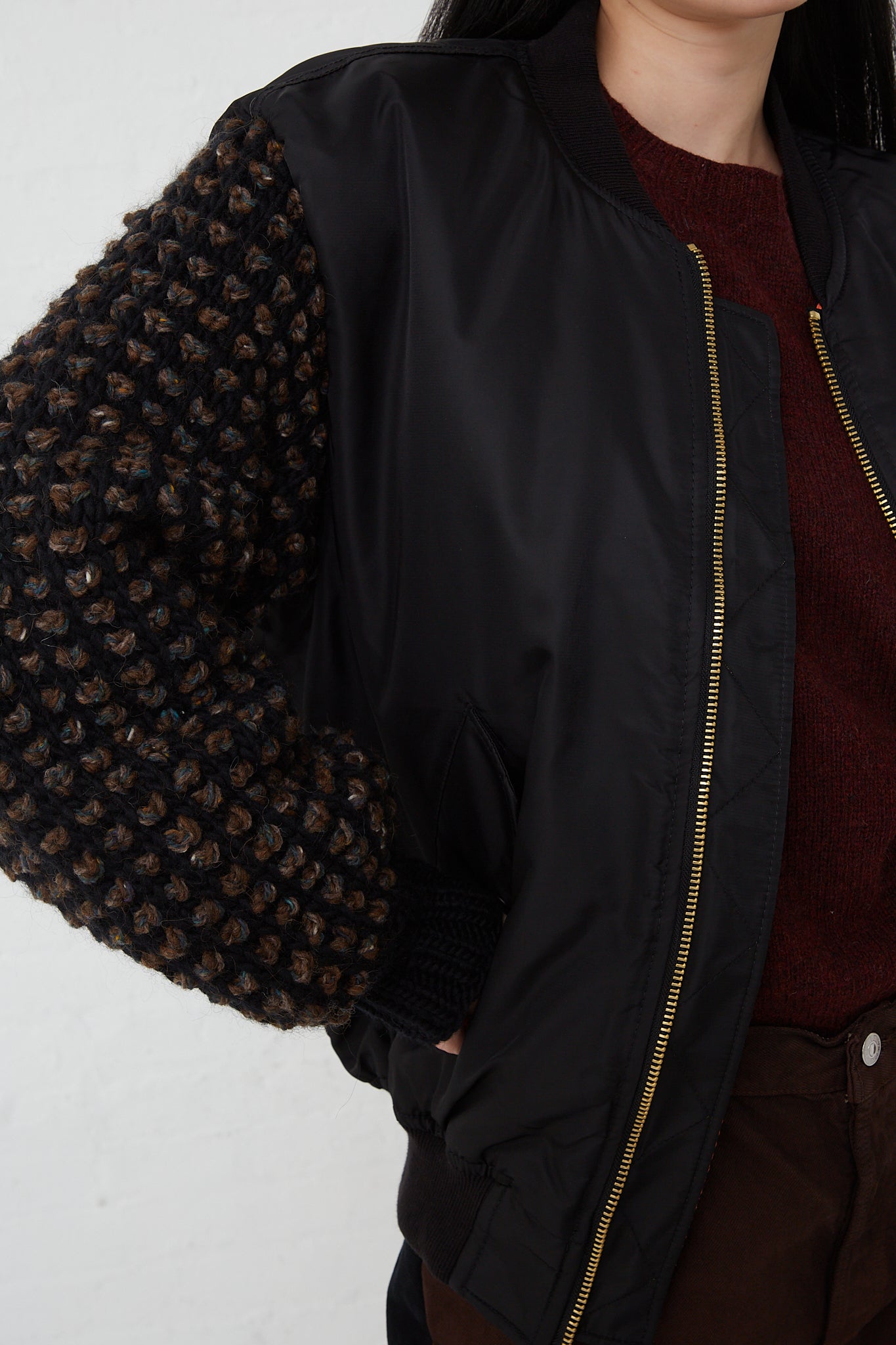 A woman with a Bless Sleeve Bomber No. 70 in Black, paired with brown pants.
