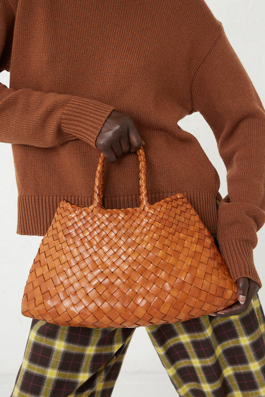 A woman is holding a Dragon Diffusion Santa Croce Small Bag in Tan made of buffalo leather.