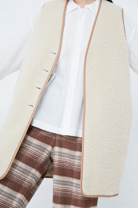 A woman wearing a Toujours Silk Gabardine Reversible Padded Liner Long Vest in Sand with front button closure.