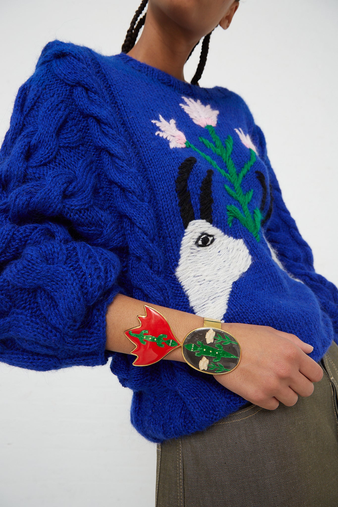 A woman wearing a blue sweater with an enamel Sofio Gongli cuff bracelet in Alligators.