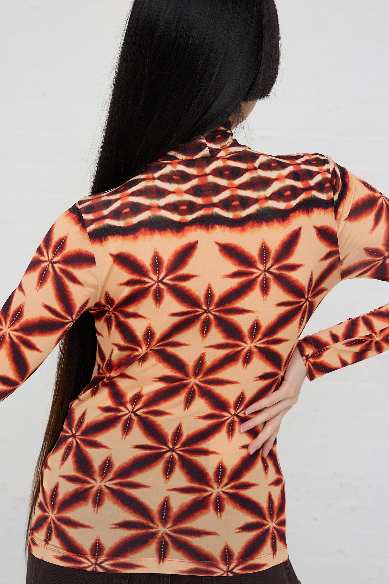 A woman wearing an Ulla Johnson Aurelia Turtleneck in Andromeda with a printed pattern. Back view.