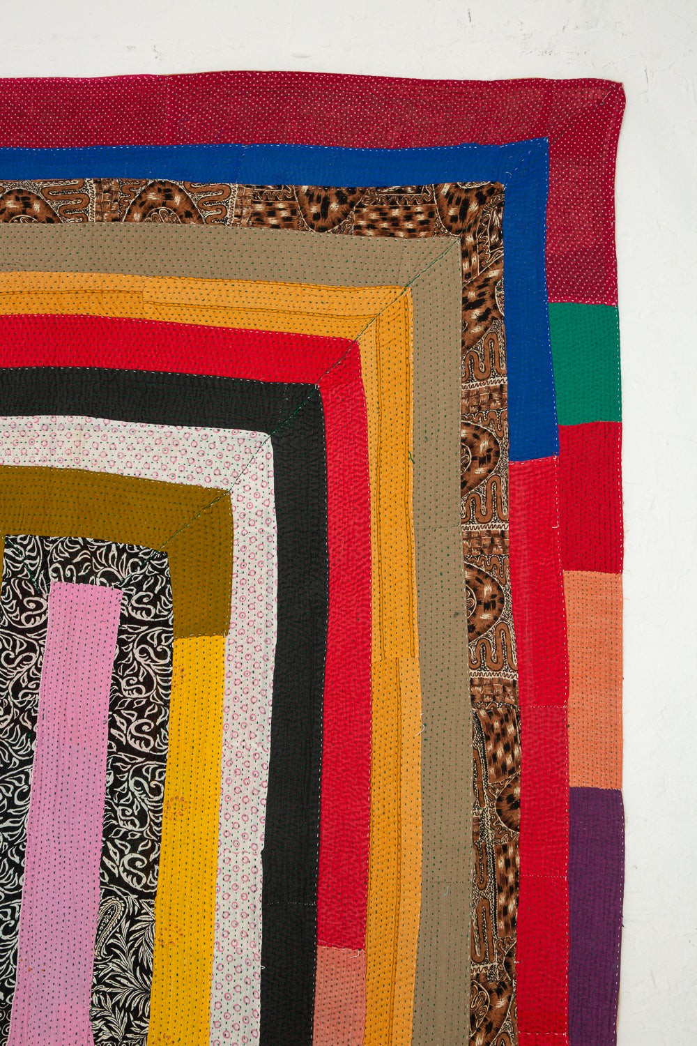 A colorful quilt is laid out on a white surface.