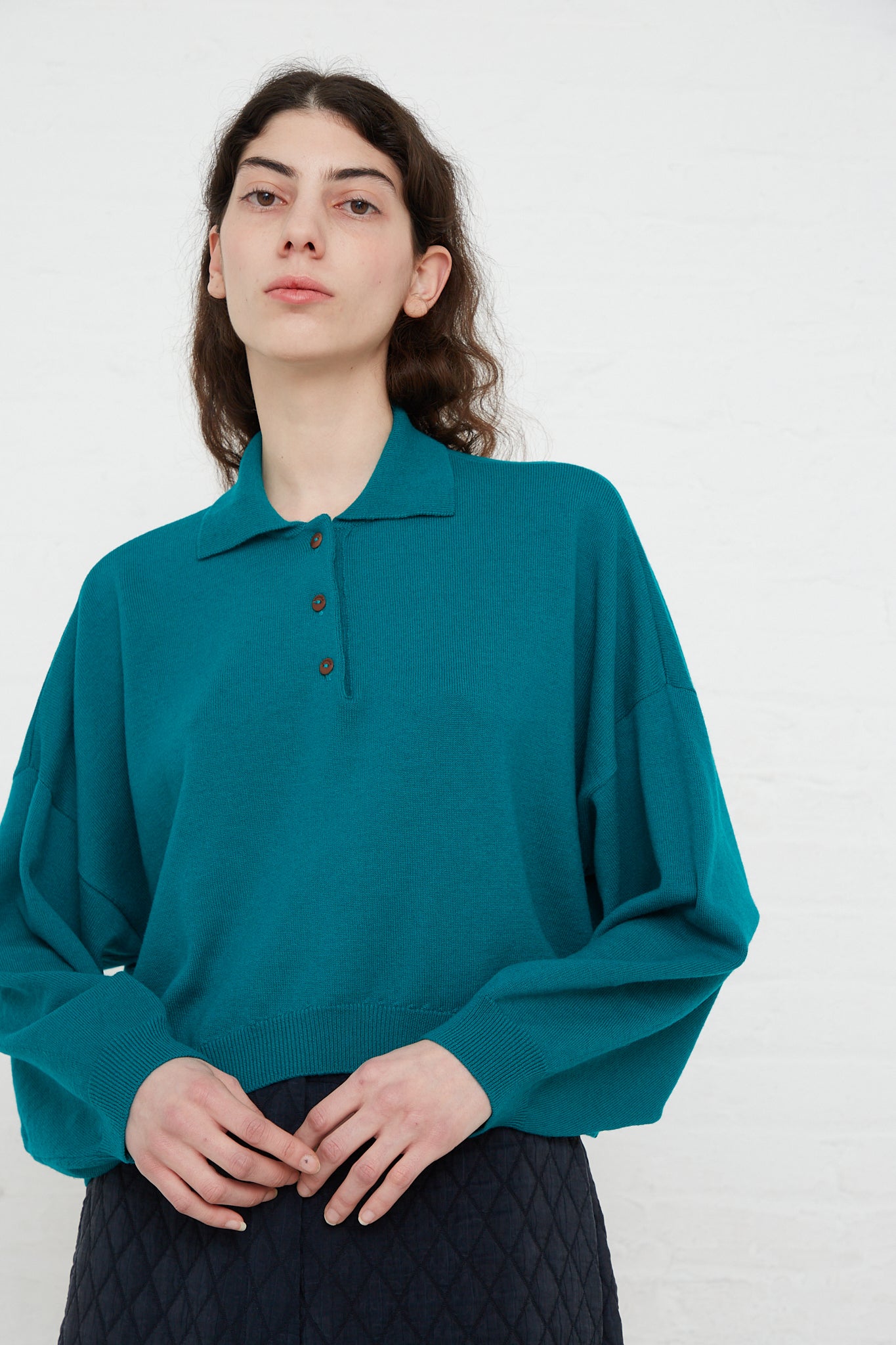 The model is wearing a Cordera Merino Wool Polo Sweater in Teal Green made in Spain.