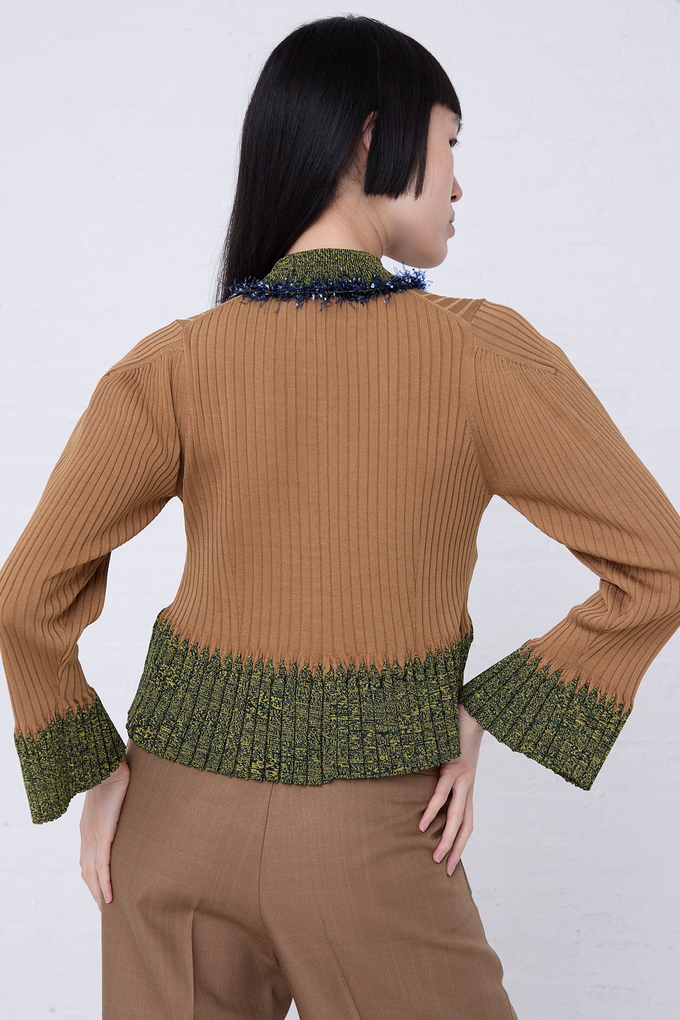 The back view of a woman wearing a TOGA PULLA Wide Rib Knit Cardigan in Beige.