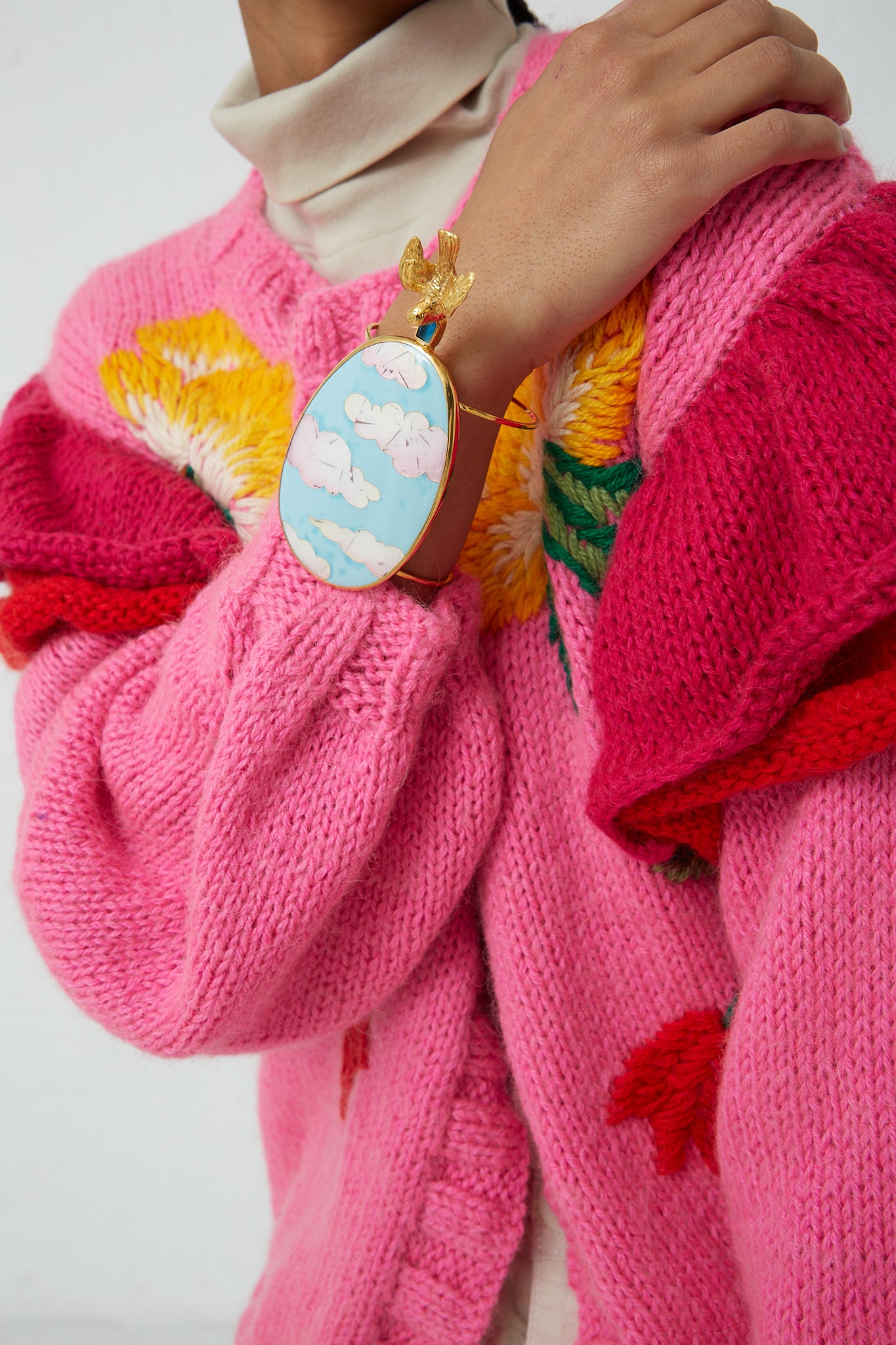 A woman wearing a pink sweater and a pink Sofio Gongli Bracelet in Clouds with Bird.