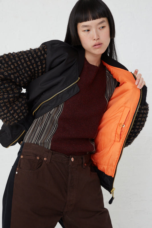 A woman in brown pants and an oversized-fit Sleeve Bomber No. 70 in Black made of a nylon and wool blend, by Bless.
