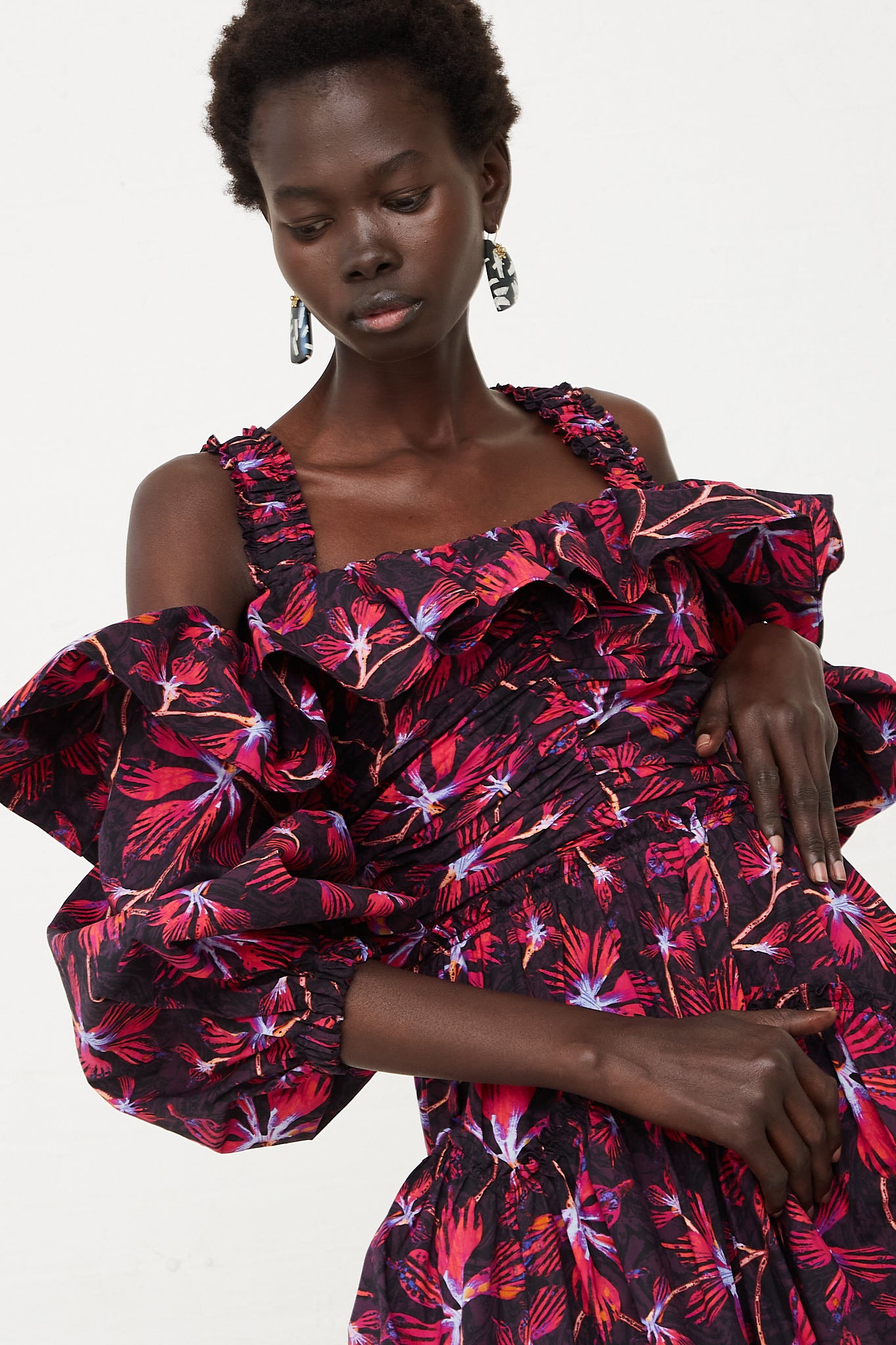 The model is wearing a Caprice Midi Dress in Zinnia by Ulla Johnson, featuring vivid shades of magenta and hyacinth floral print.