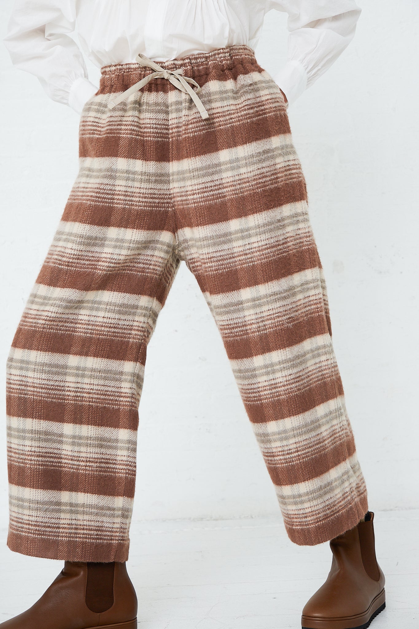 A woman wearing Toujours Silk Plaid Mosser Cloth Pajama Pants in Cocoa Brown. Up close view.
