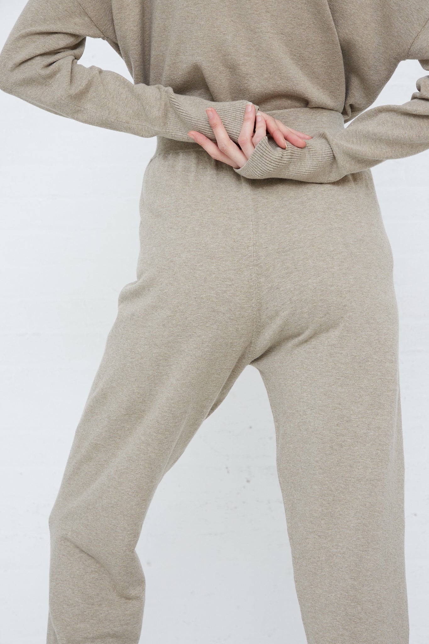 The model is wearing the Lauren Manoogian Base Pant in Stone Melange, a relaxed fit pant in soft pima cotton. Back view and up close. Model's arms are crossed behind her back.