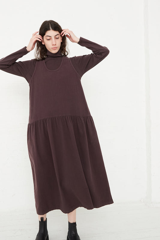 The model is wearing a long-sleeved Cotton Woven Tank Dress in Plum by Black Crane.