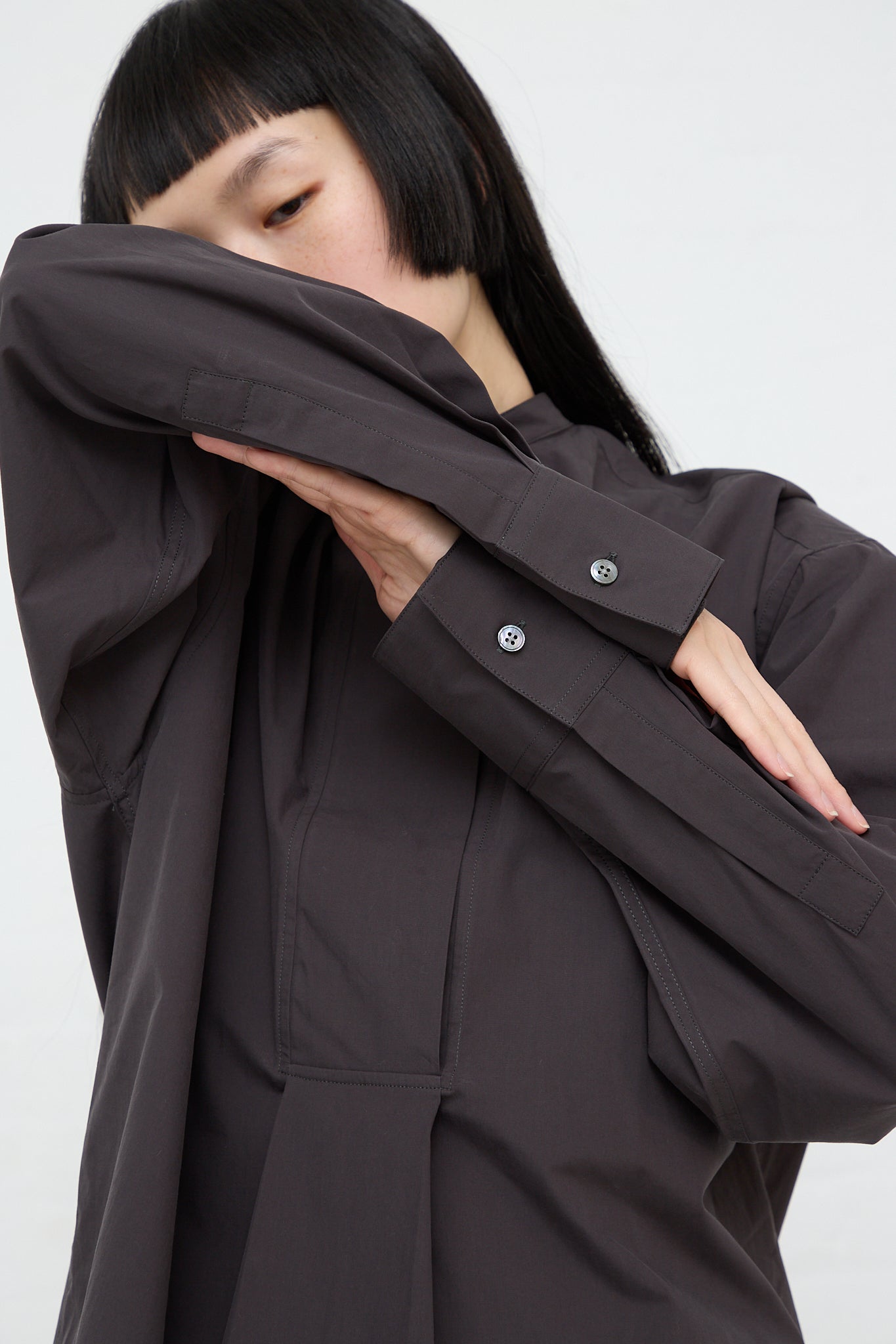 A woman wearing a Studio Nicholson Frink Half Placket Shirt in Asphalt.