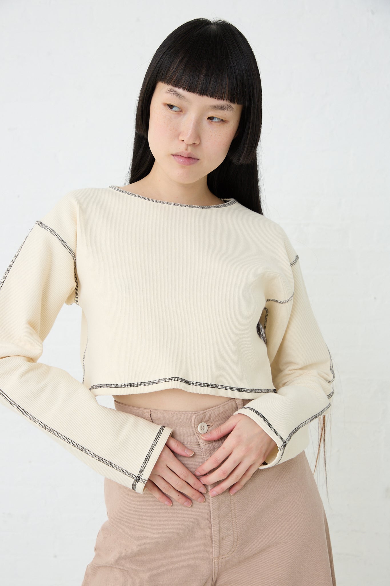 A model wearing a Cotton Hemp Rib Garble Top in Undyed, sustainably produced by Baserange, paired with pink pants. Front view.