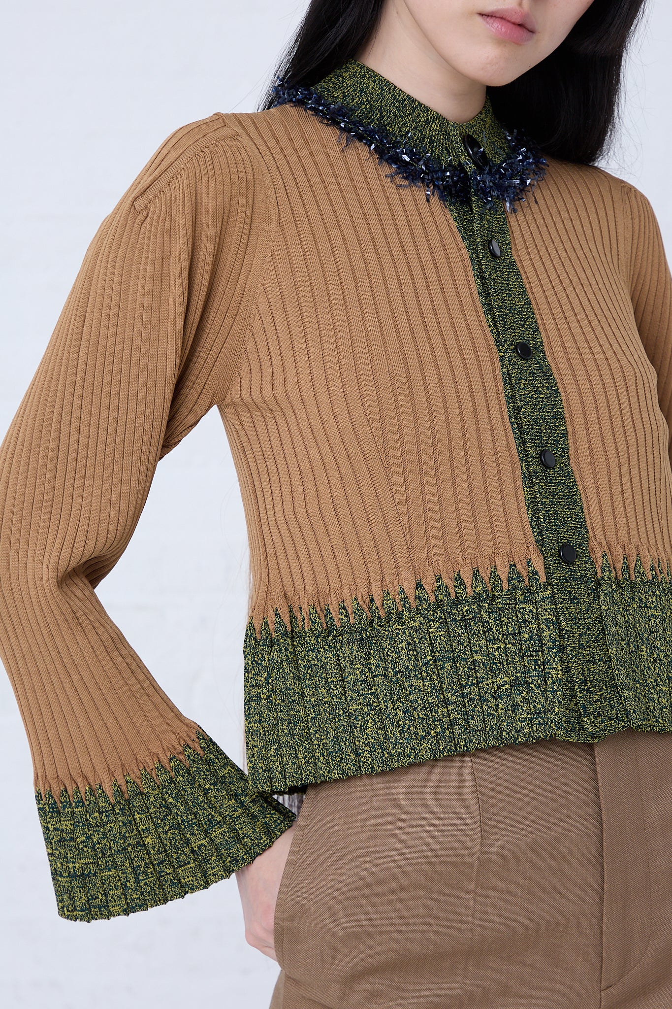 A woman wearing a TOGA PULLA wide rib knit cardigan in beige and green sweater.