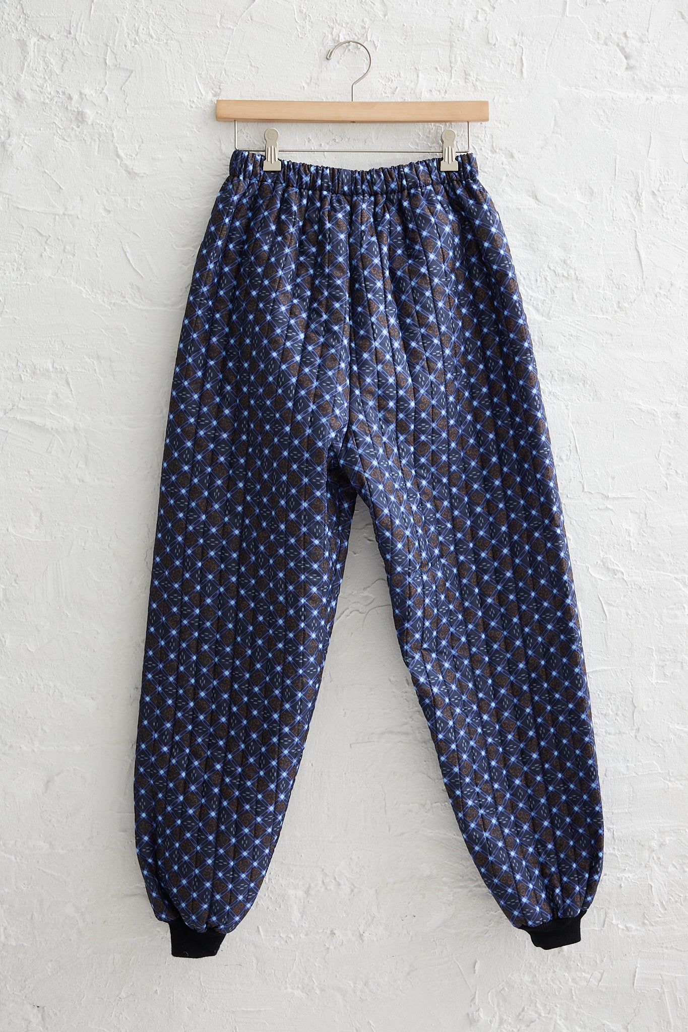 A pair of Bless Monpe Pant No. 08 in Floral Print B - S with an elasticated waist hanging on a white wall.