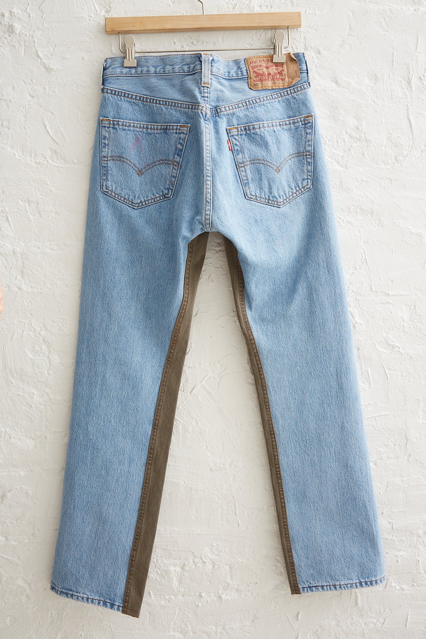 A pair of Bless Jeanspleatfront No. 73 in Surprise Color Mix A with a 5-pocket design hanging on a white wall.