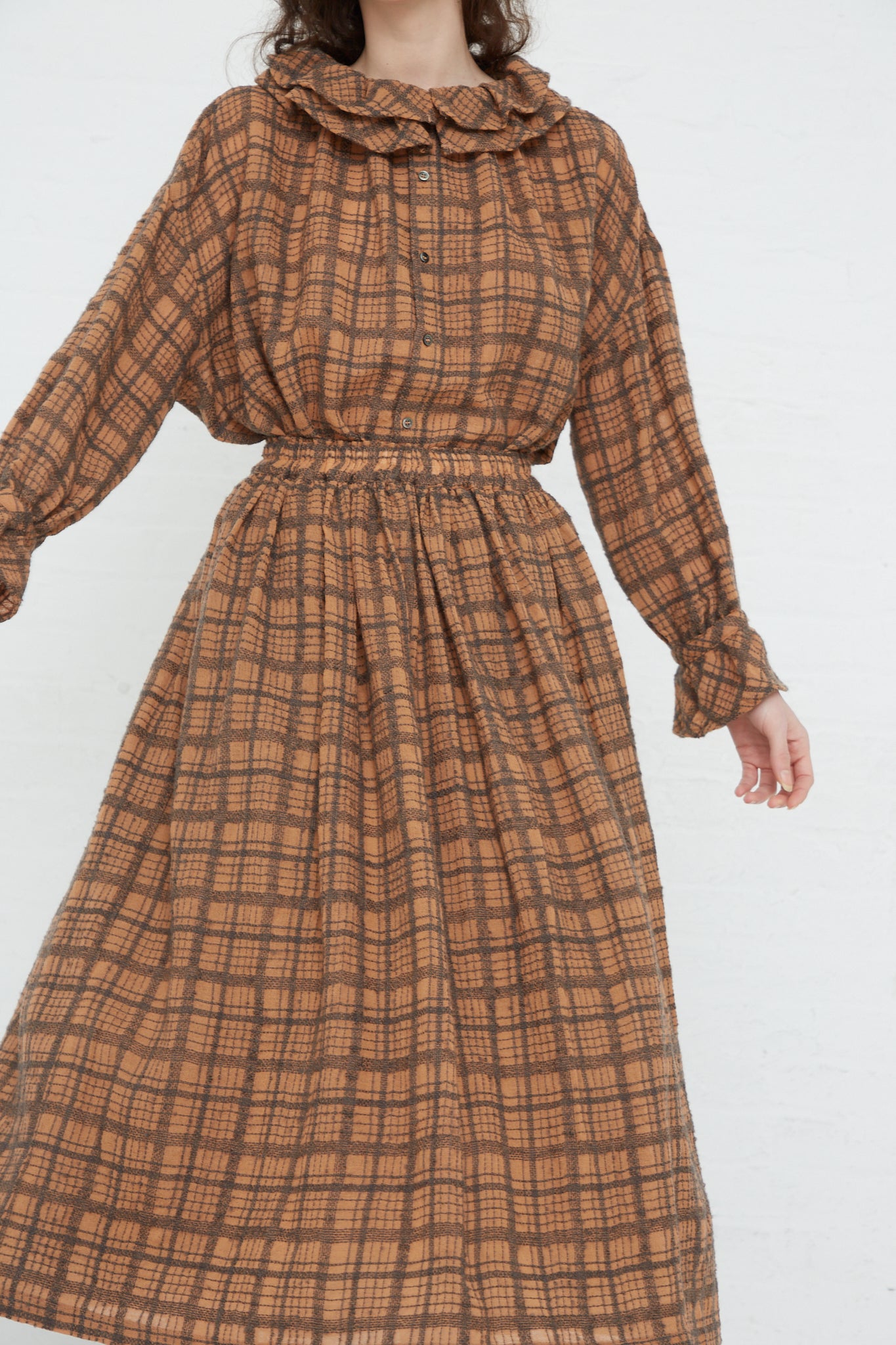 A woman wearing an Ichi Antiquités Woven Wool Check Skirt in Terracotta made of woven check wool fabric.