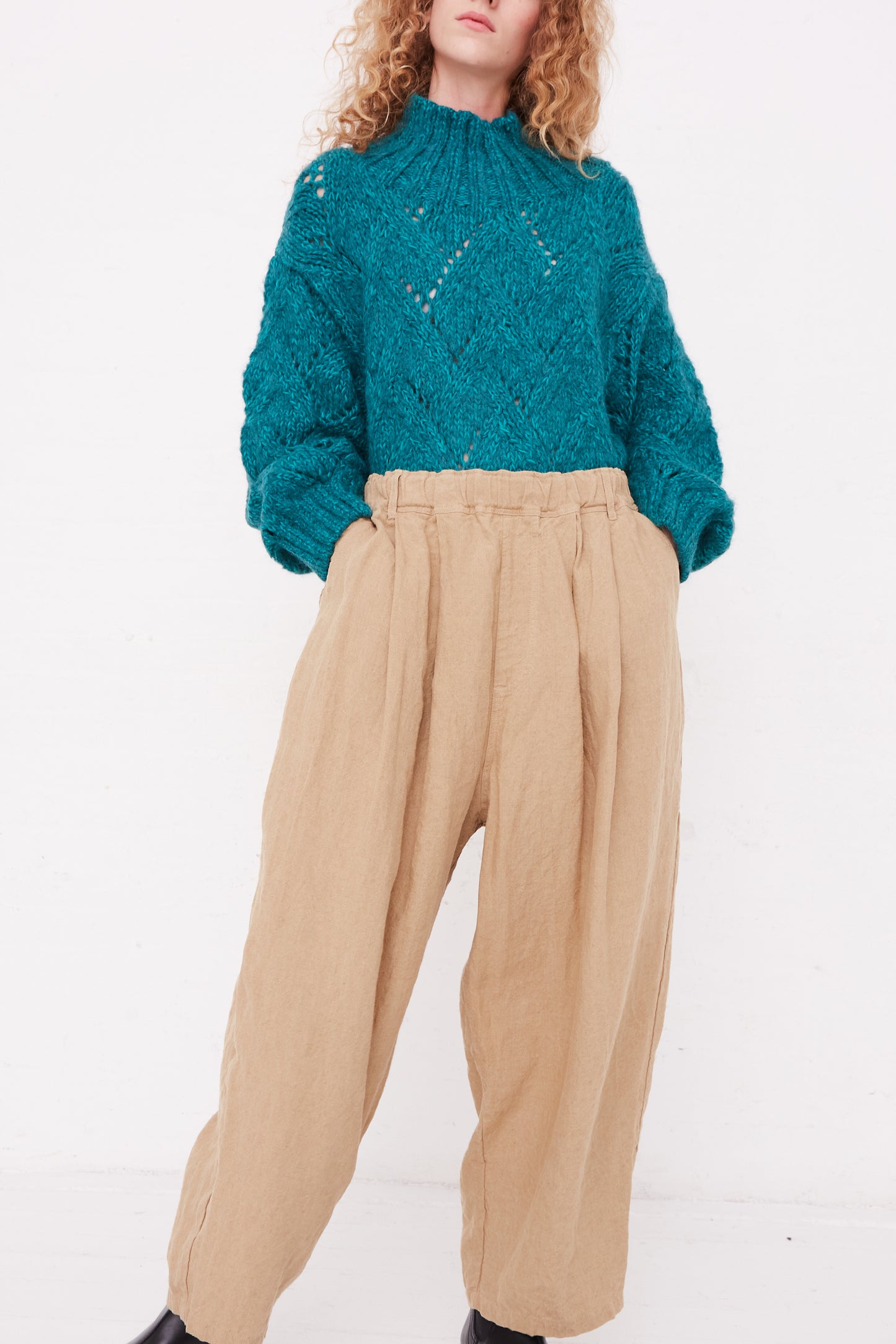 A model wearing Ichi Antiquités' Linen Canvas Pants in Beige pants in a teal sweater.