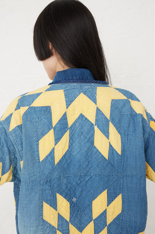 The back of a woman wearing an As Ever Quilt Jacket in Indigo and Yellow.
