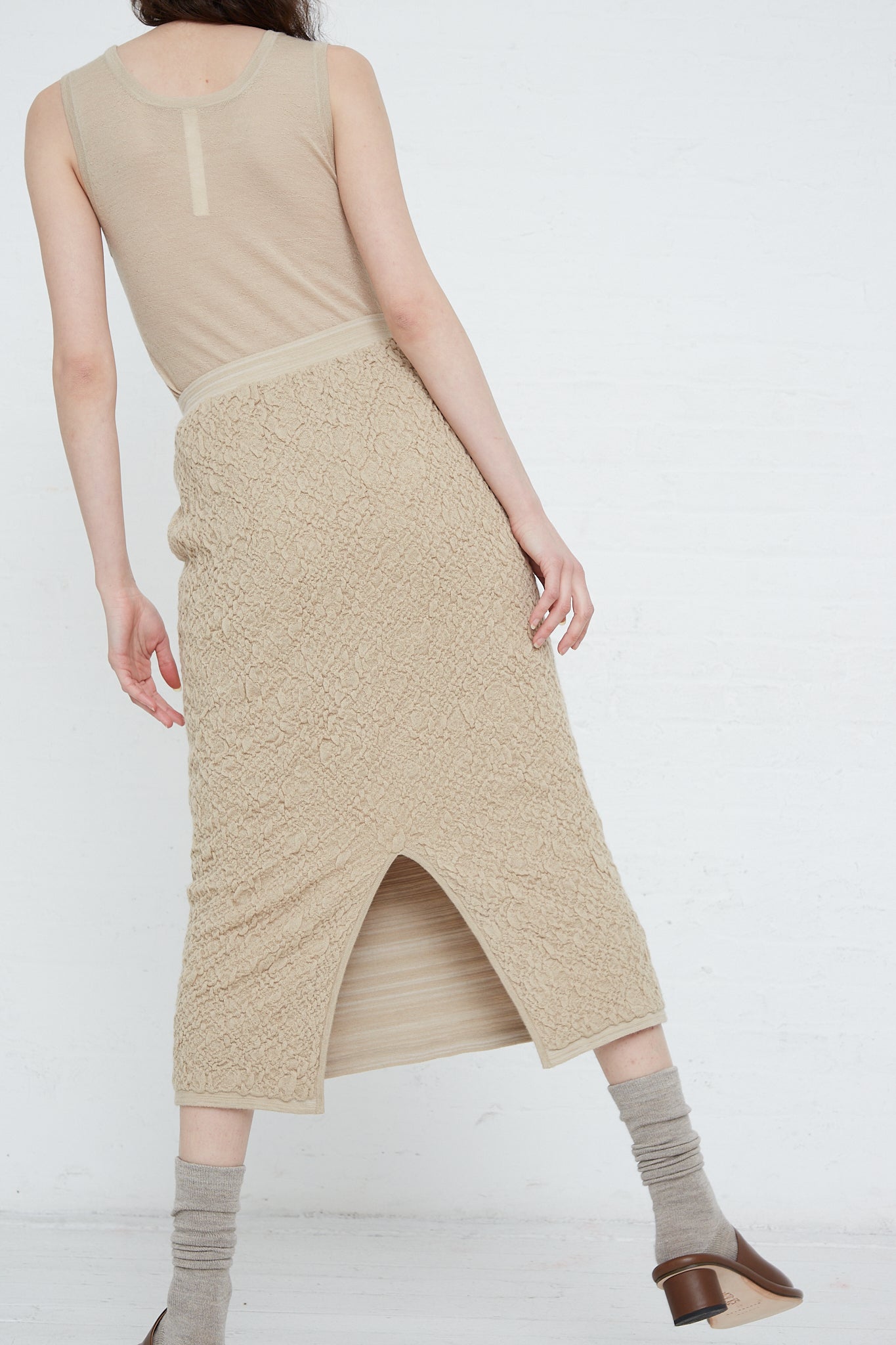 The model is wearing a Baby Alpaca Gauze Skirt in Antique by Lauren Manoogian with a slit. Back view.