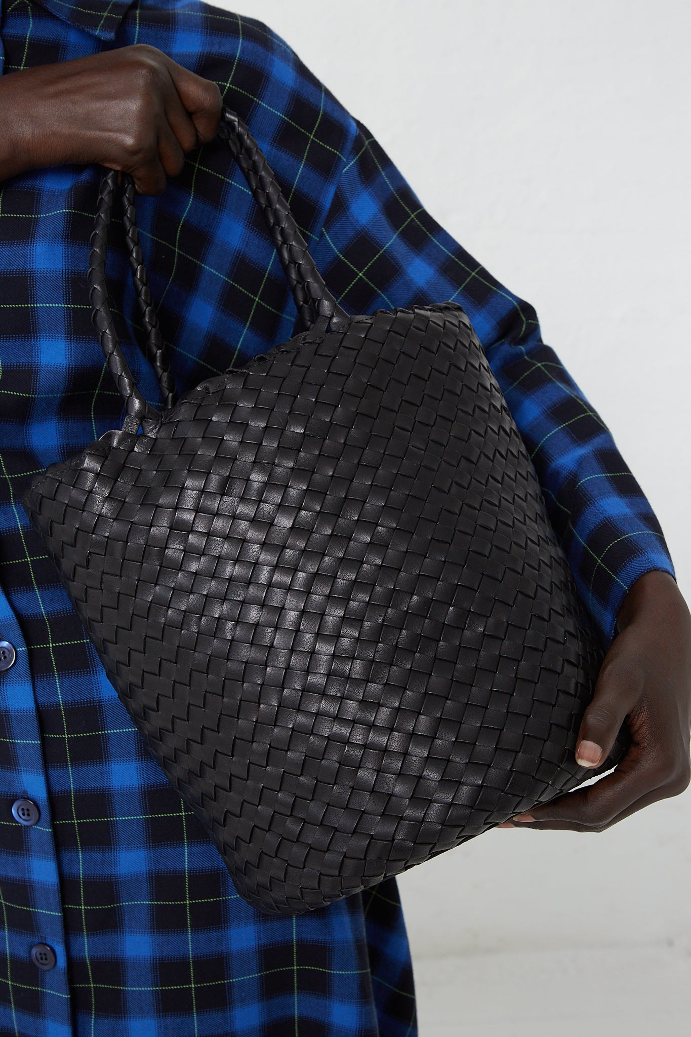A woman is holding a Dragon Diffusion Jacky Bucket Bag in Black. Available at Oroboro Store.