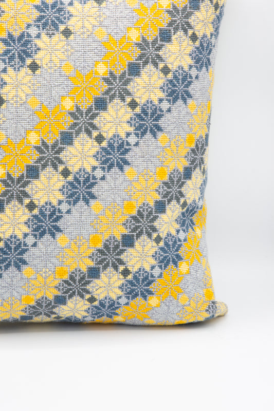 A Kissweh Moon of Bethlehem Hand Embroidered Pillow in Slate and Lemon, with a yellow and grey geometric pattern, featuring hand embroidery. Up close view.
