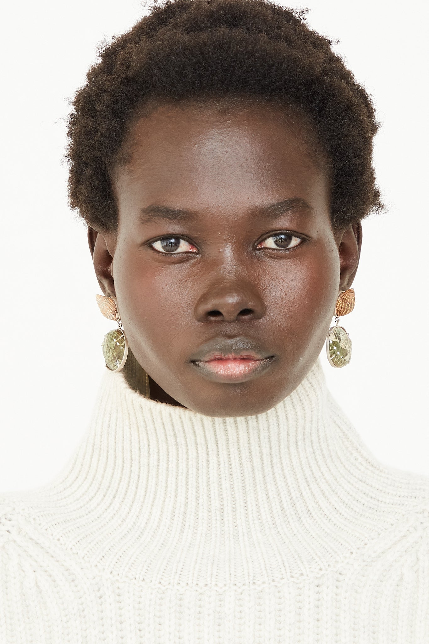 A model in NYC wearing La Mar's Sterling Silver Shell Earrings 010 and a white turtleneck sweater.