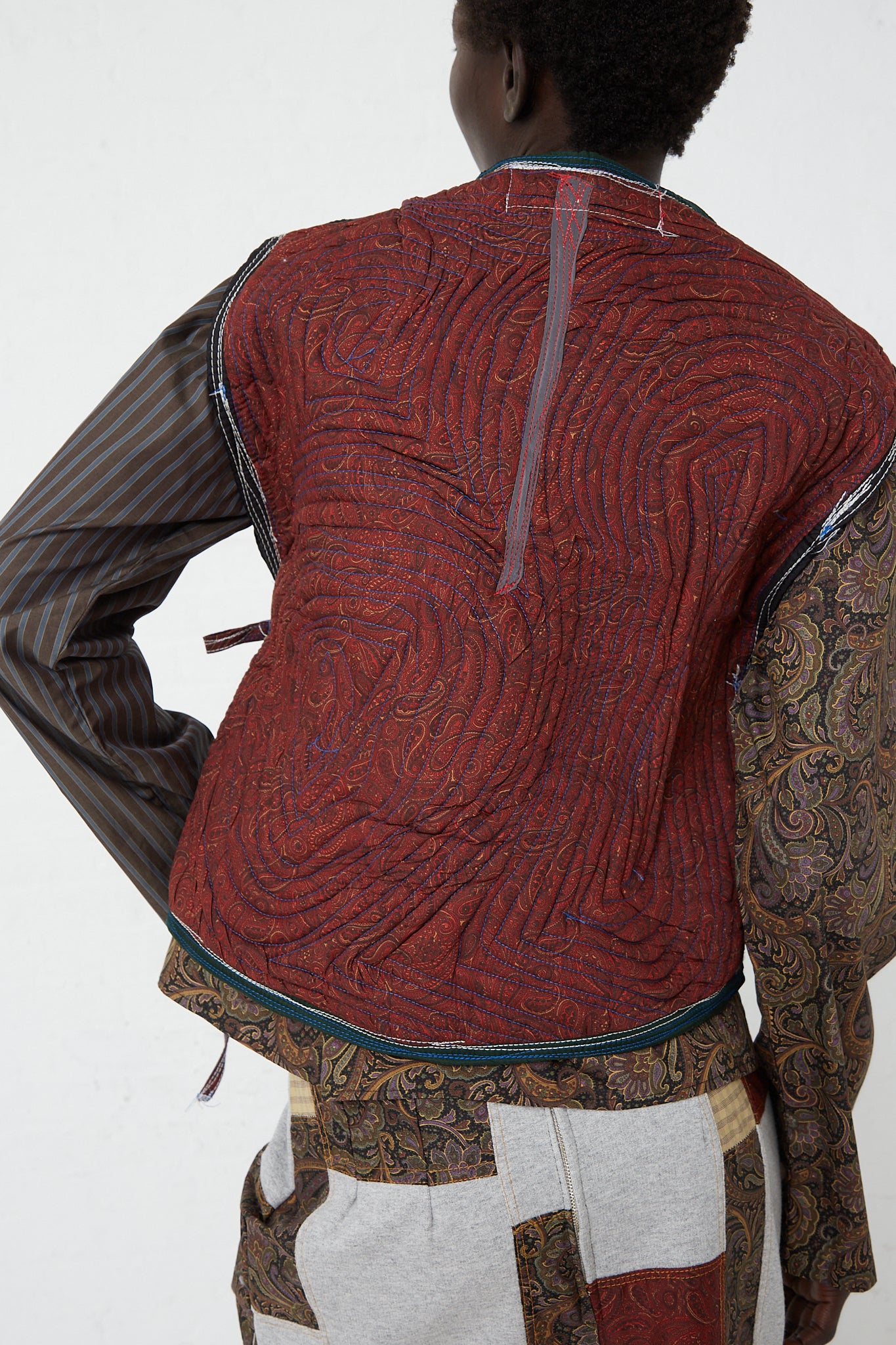 The back of a woman wearing a Paisley Poplin Boulder Vest in Lava by SC103 and relaxed fit pants.
