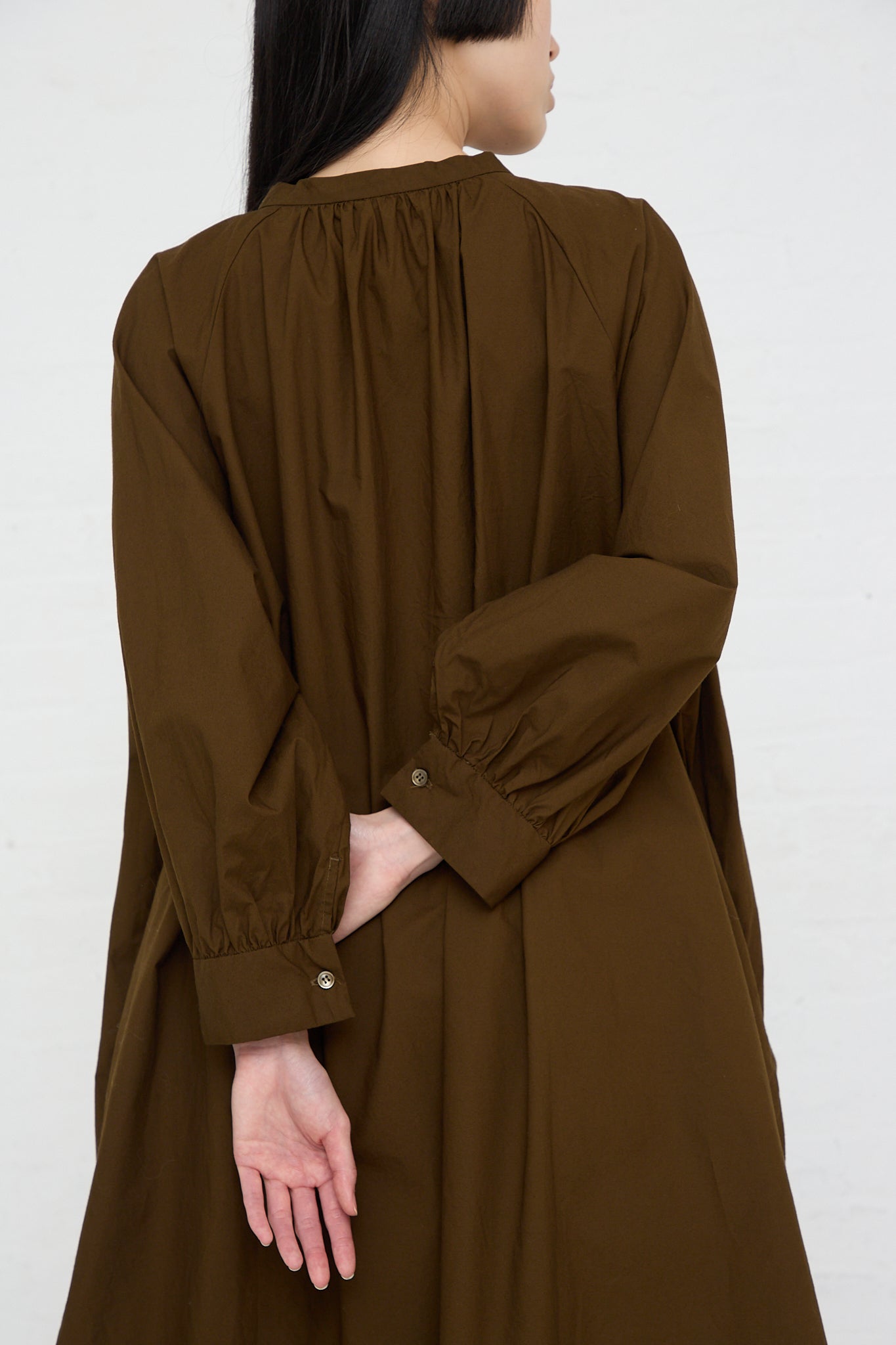 The back view of a woman wearing an Ichi Woven Cotton Shirt in Seal Brown with wide band collar.