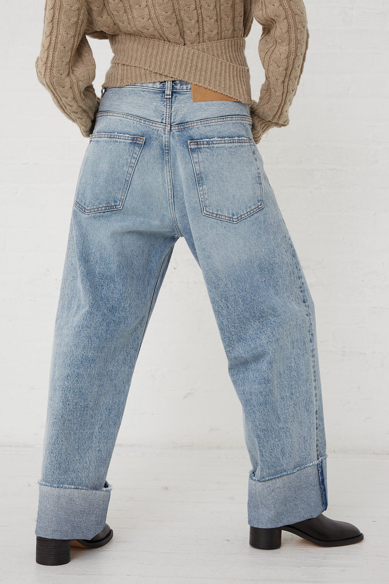 The back of a woman wearing MM6 high waisted jeans and a relaxed fit 5 Pocket Pant in Light Indigo sweater.