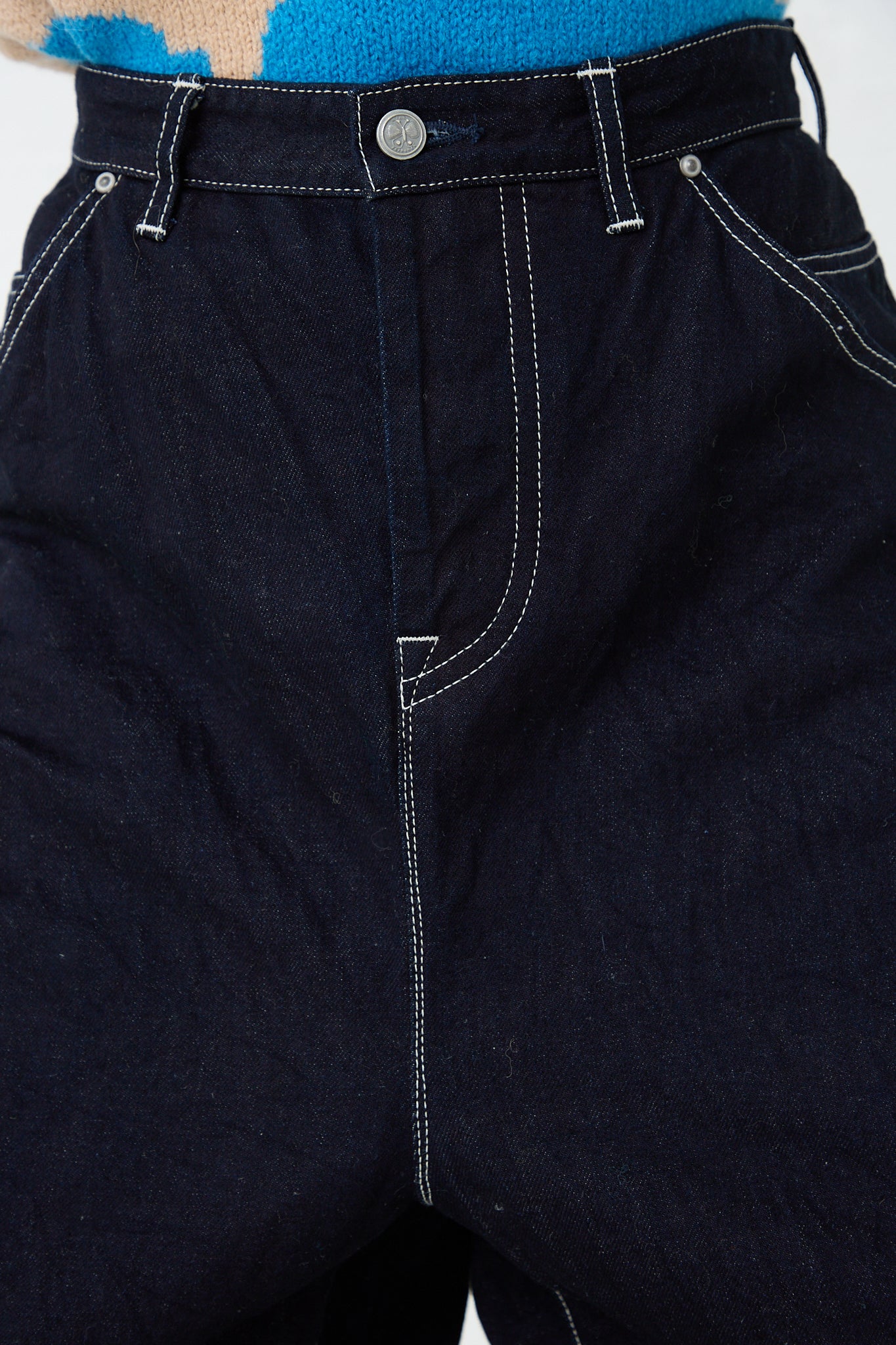 The front of a woman wearing a Mina Perhonen Always Balloon Wide Pant in Indigo. Up close view of pant stitching and button details.