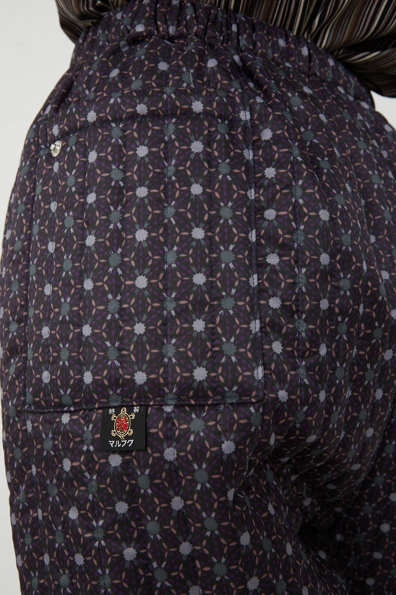 The back view of a model wearing a pair of Bless Monpe Pant No. 08 in Floral Print A - L with a floral printed nylon pattern and an elasticated waist.