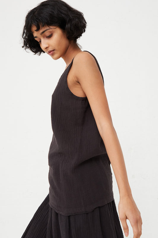A model wearing a relaxed fit scoop neck tank top in Black Crane and pleated skirt. Side profile.