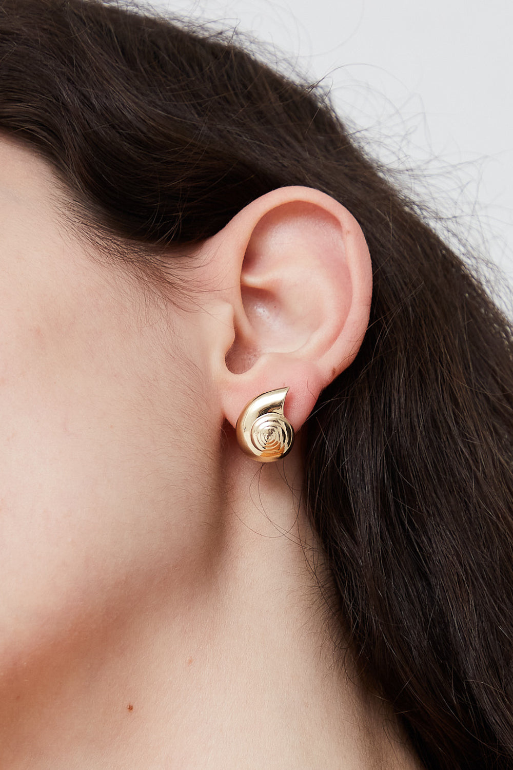 A woman's ear with a Kathryn Bentley 14k yellow gold Large Nautilus Stud Earring.