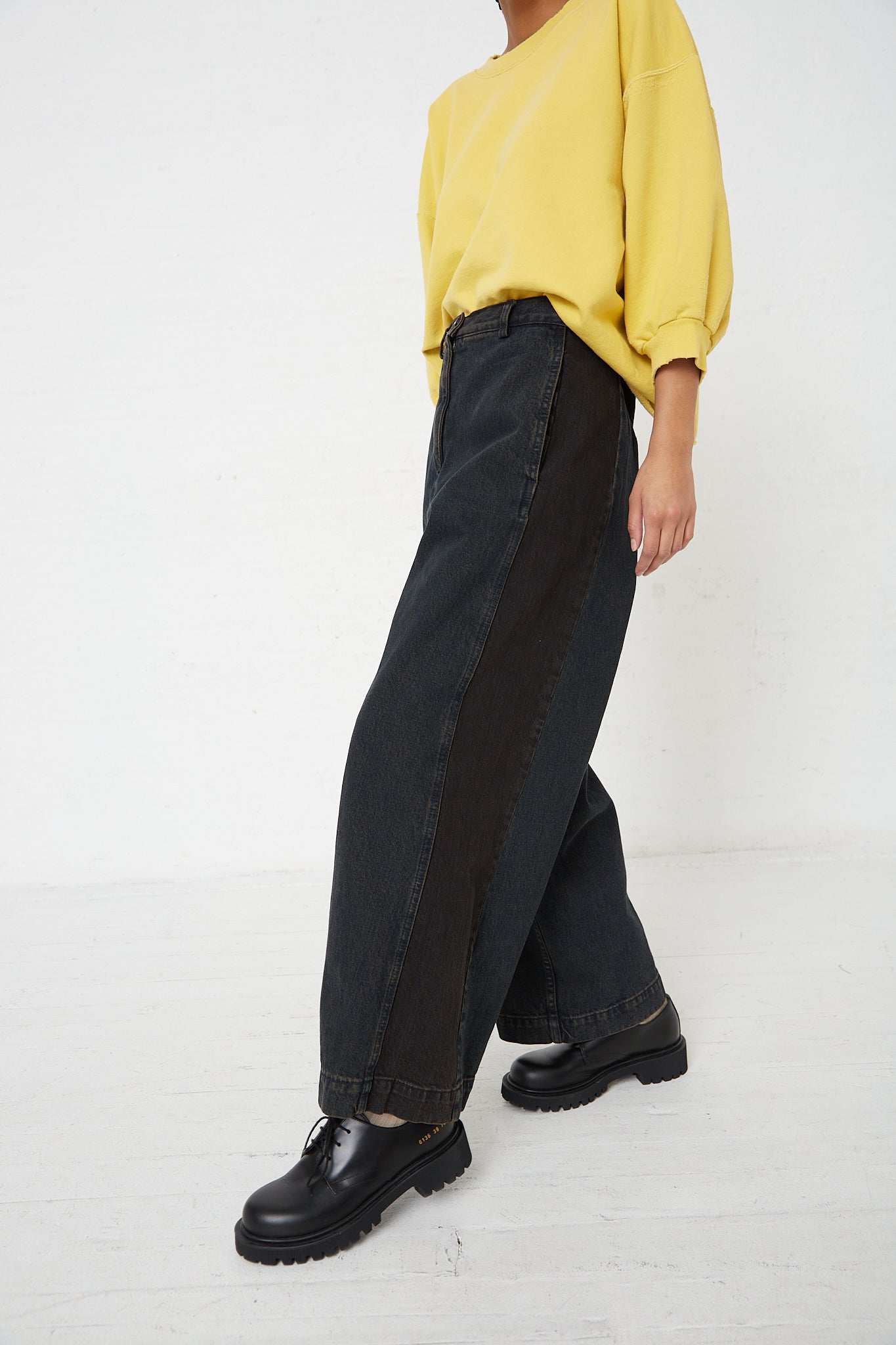 A woman wearing a yellow sweater and Rachel Comey's Denim Garra Pant in Brown.