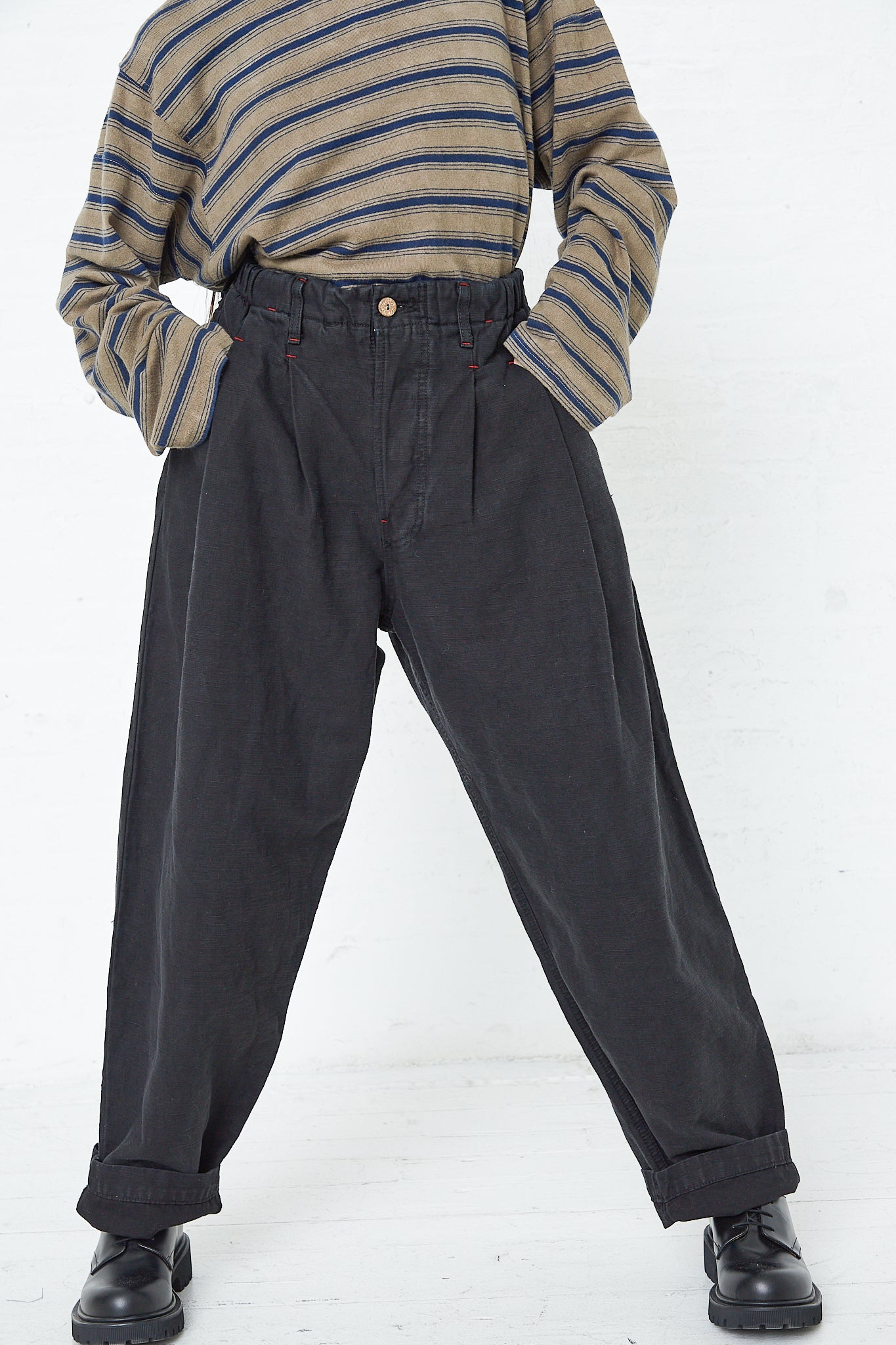A woman wearing a striped shirt and the Dr. Collectors 9 oz. Cotton and Hemp P40 Z Boys Military Pant in Sulfur Black with an elasticated waistband.