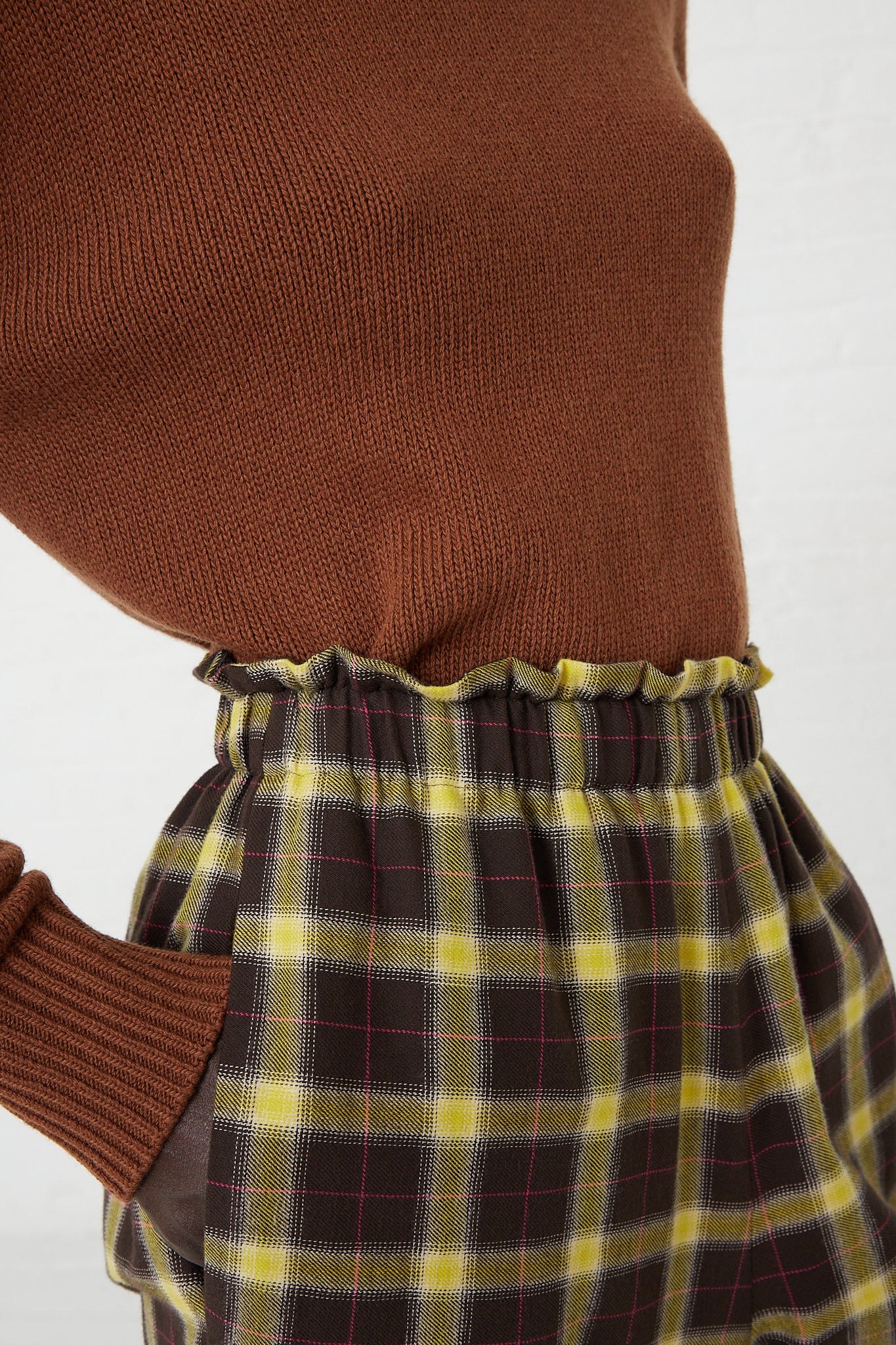 A woman wearing AVN's Easy Pant in Check Brown, Yellow and Pink, a wide leg plaid pants. Up close and side view.