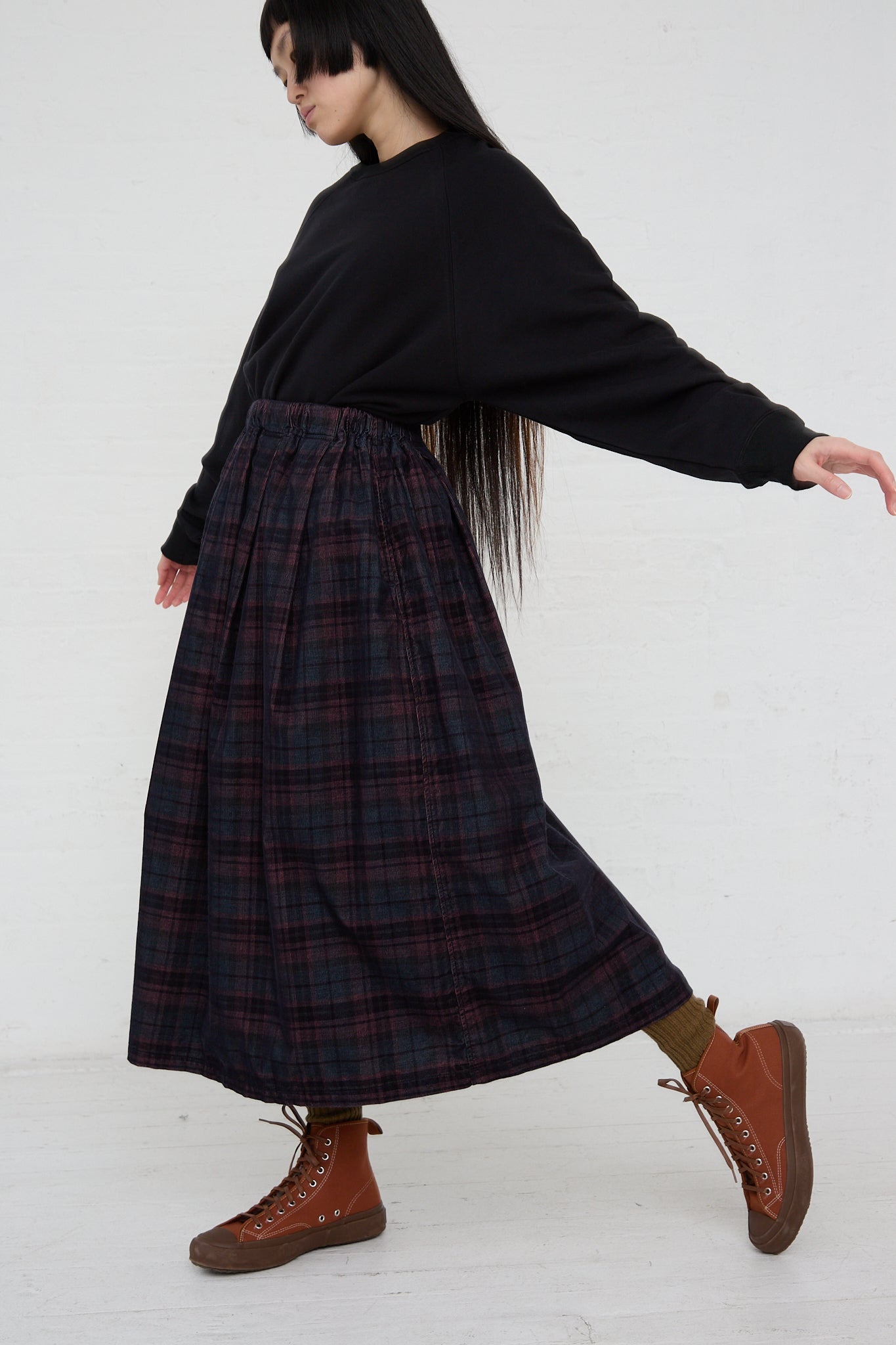 A woman in a black sweater and Ichi Woven Cotton Skirt in Navy. Side view.