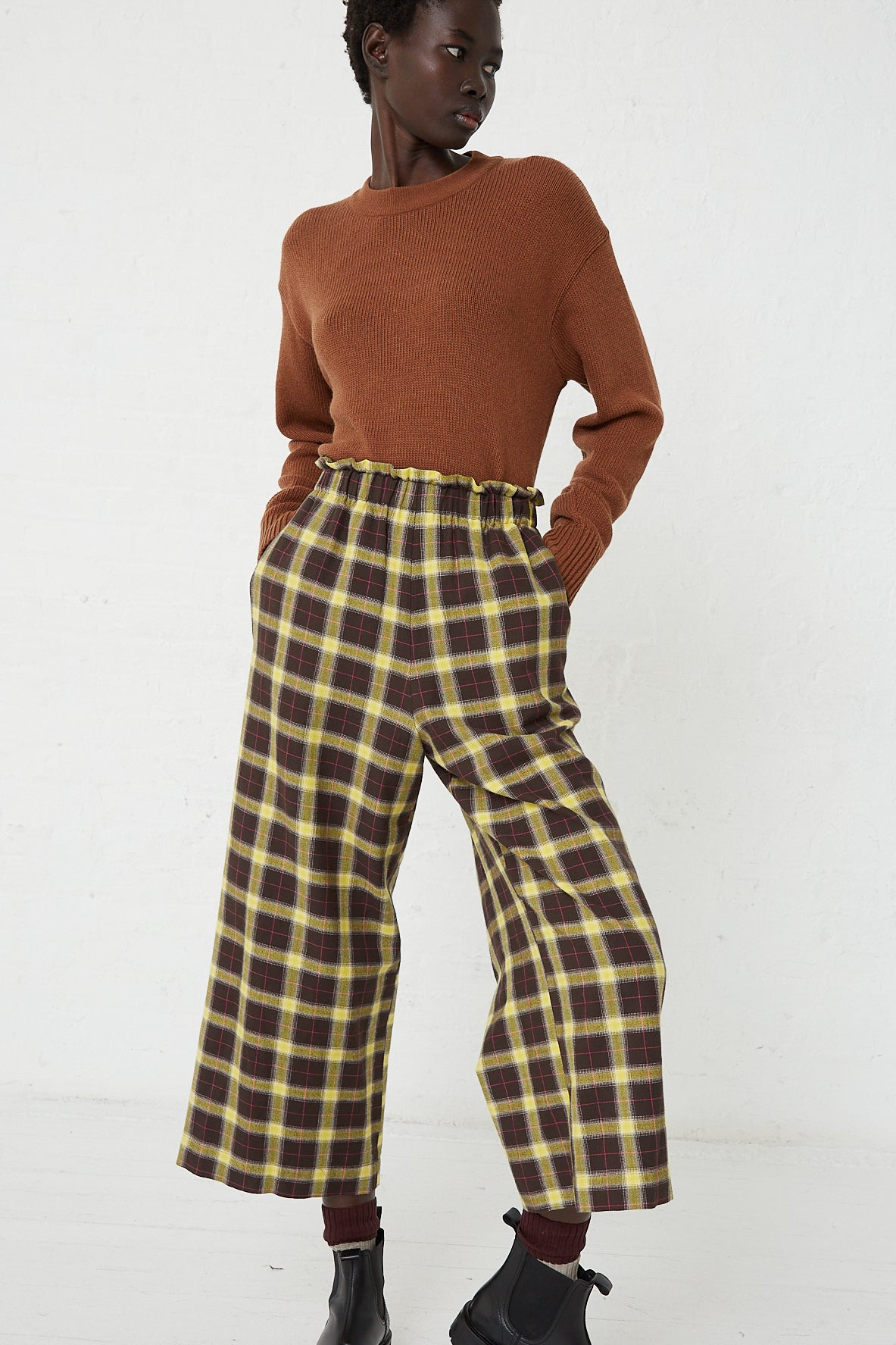 The model is wearing AVN's Easy Pant in Check Brown, Yellow and Pink, a wide leg and relaxed fit brown and yellow plaid cropped pants.