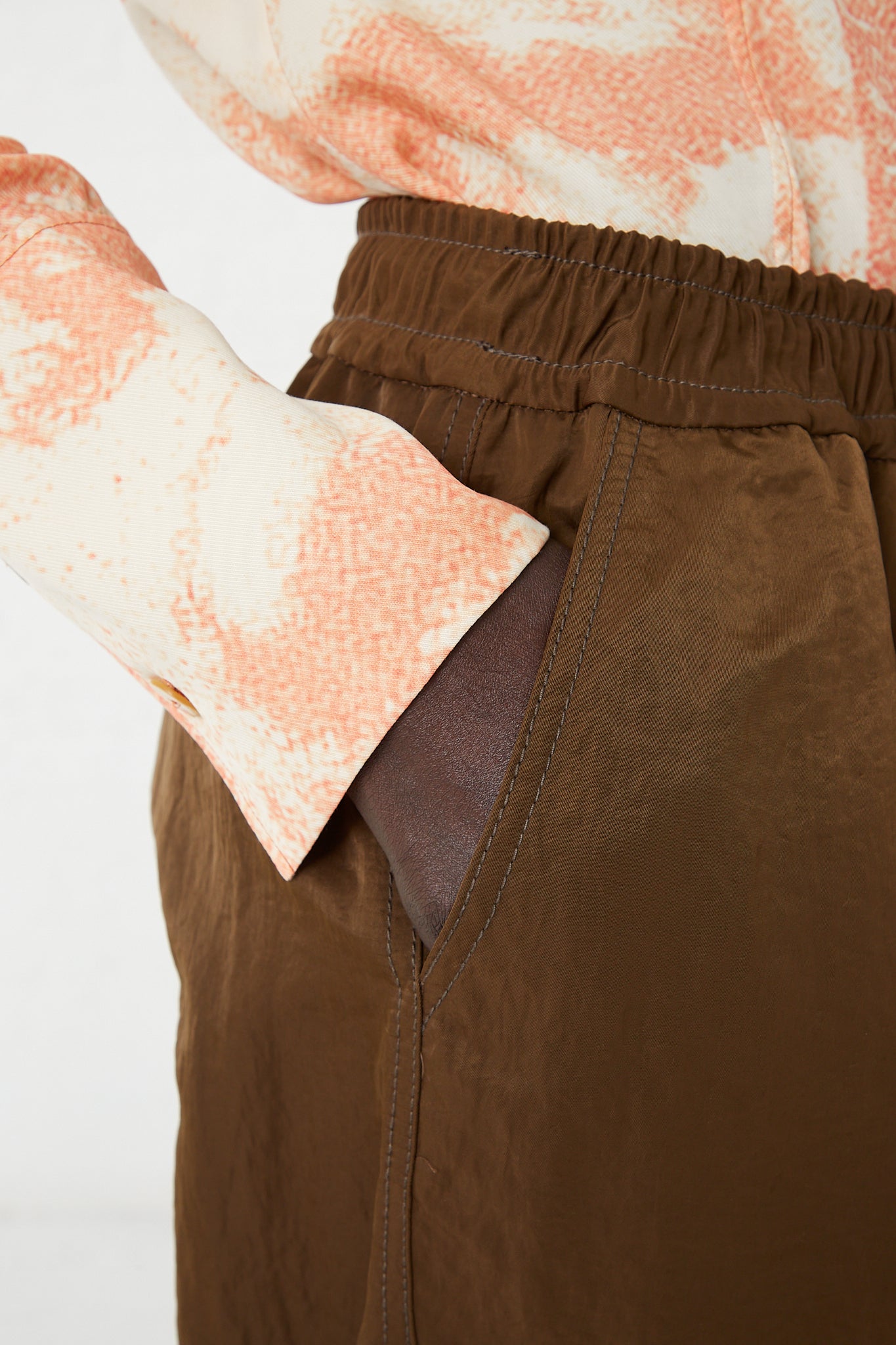 A woman in a pink shirt and Rejina Pyo's Nylon Una Trousers in Brown.
