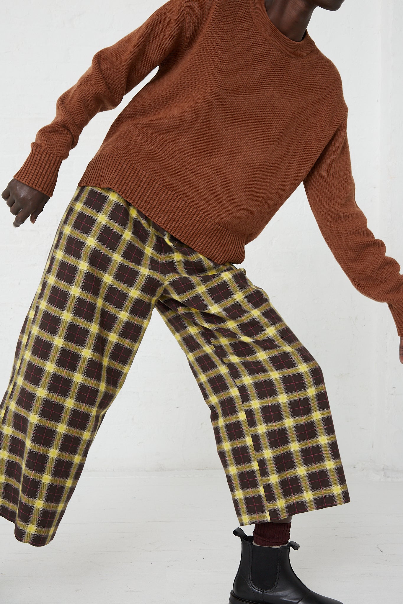 A woman in a relaxed fit AVN brown sweater and AVN yellow checkered pants with a wide leg style, the Easy Pant in Check Brown, Yellow and Pink.