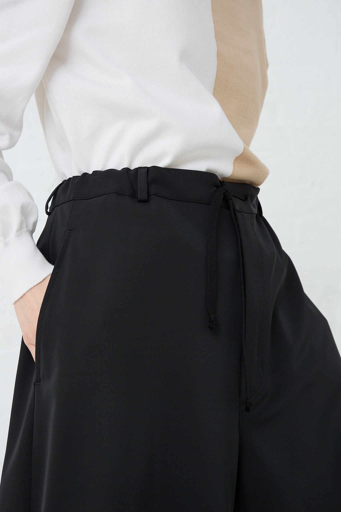 A woman wearing MM6's Pant in Black and a white shirt. Front view and up close. 