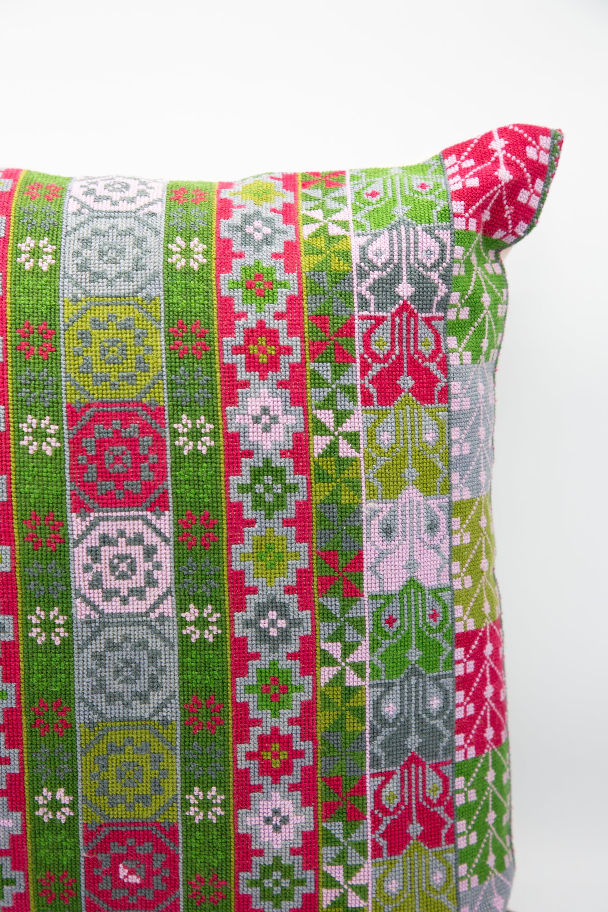 A Malak Hand Embroidered Pillow in Emerald and Crimson by Kissweh with a green and pink pattern.